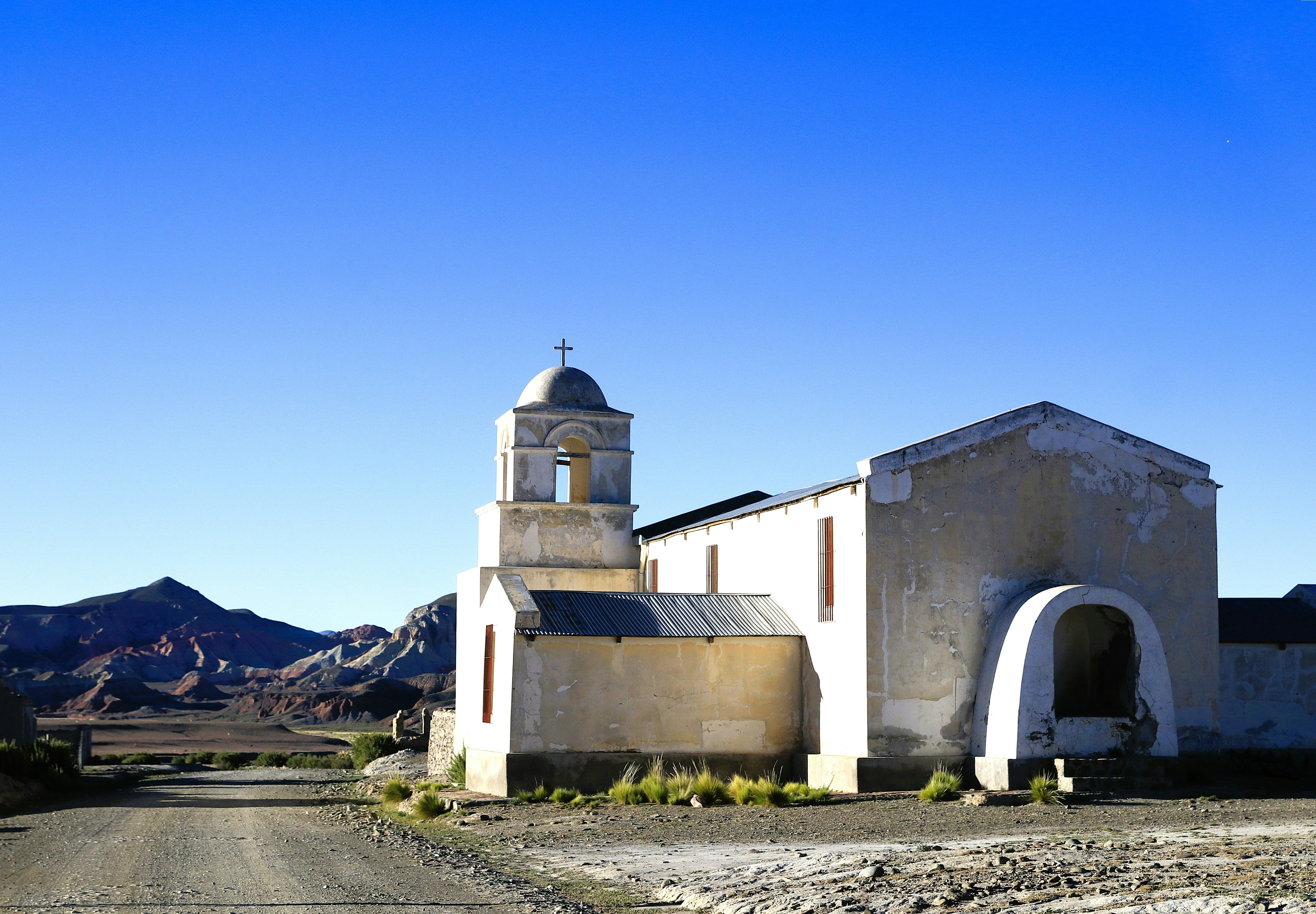 An old church sits along a dirt road.