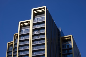 Modern skyscraper with gold trim against a blue sky.