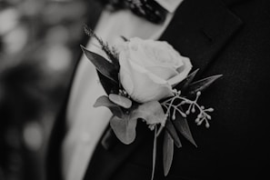 A groom wears a white rose boutonniere.