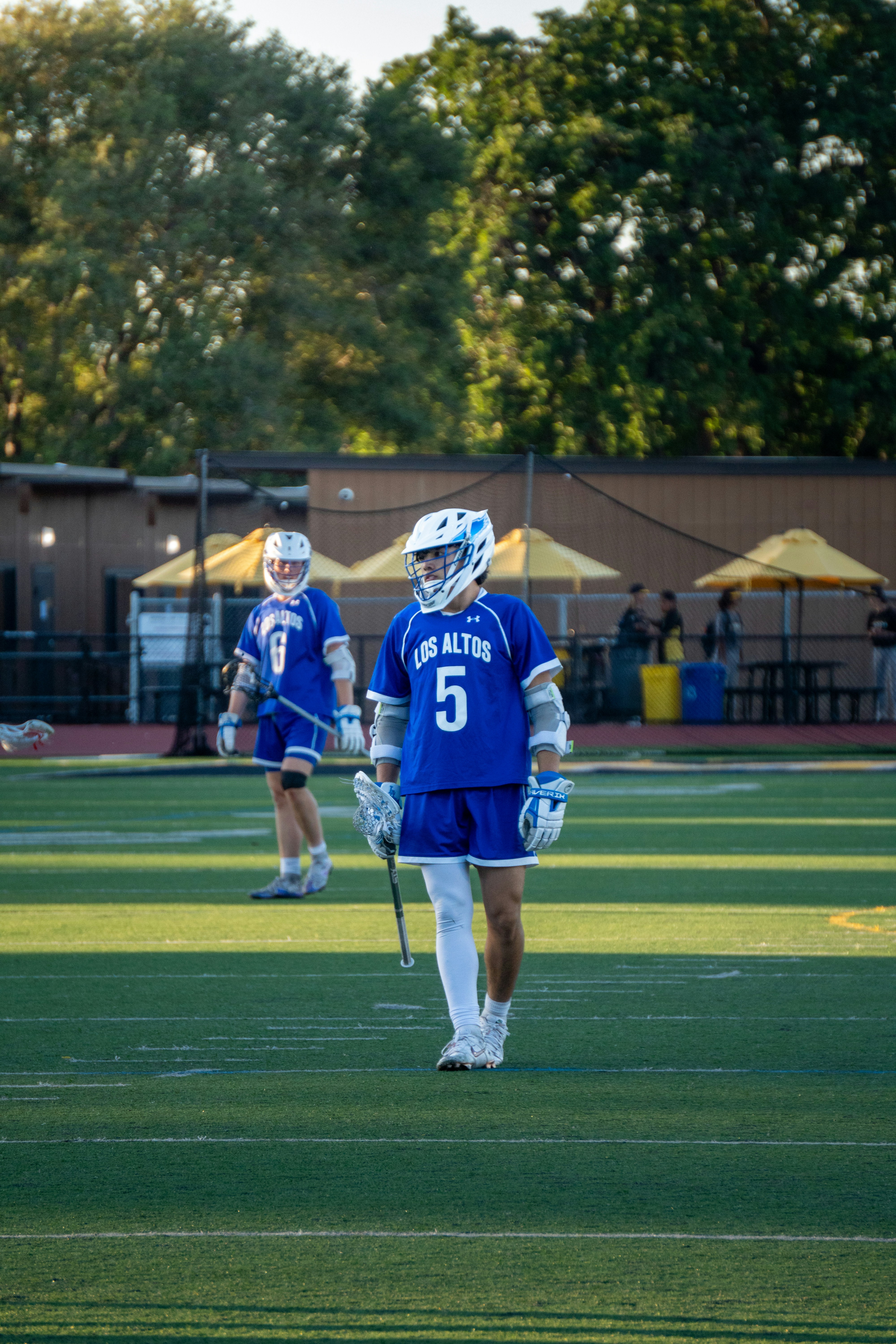 Dos jugadores de lacrosse están de pie en el campo.