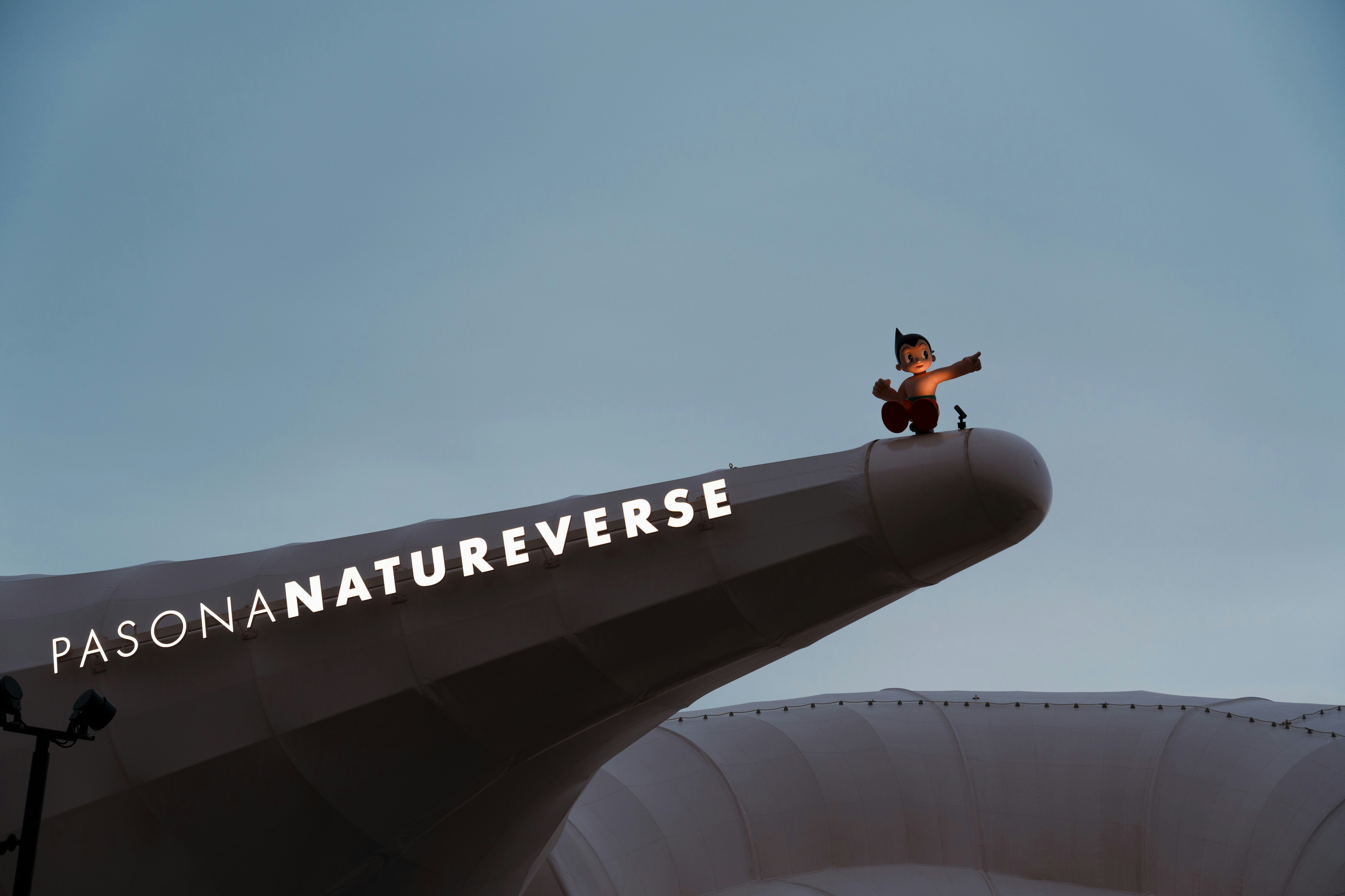 Una figura si trova in cima al cartello "pasona natureverse".