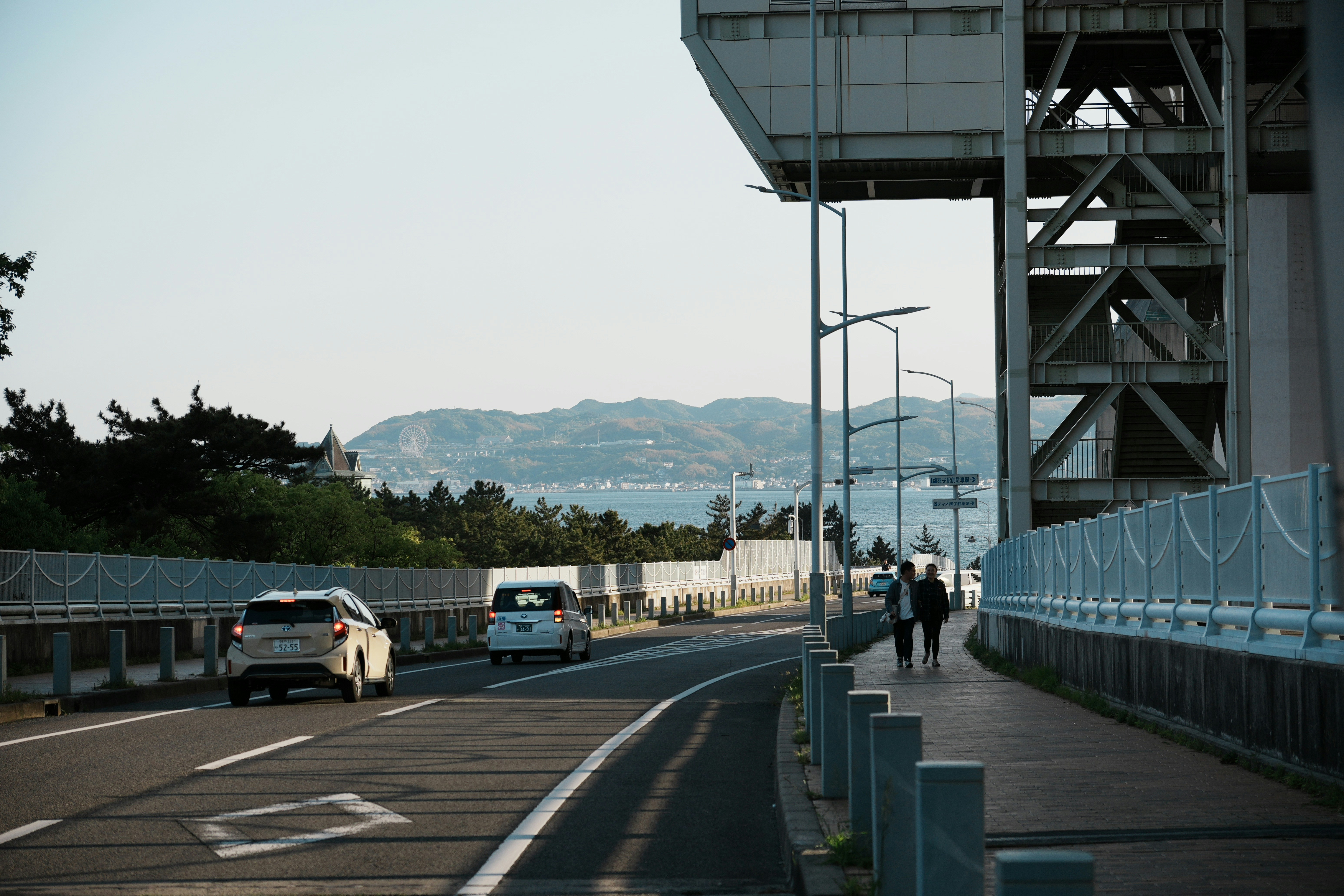 Cars drive on a bridge with an ocean view.