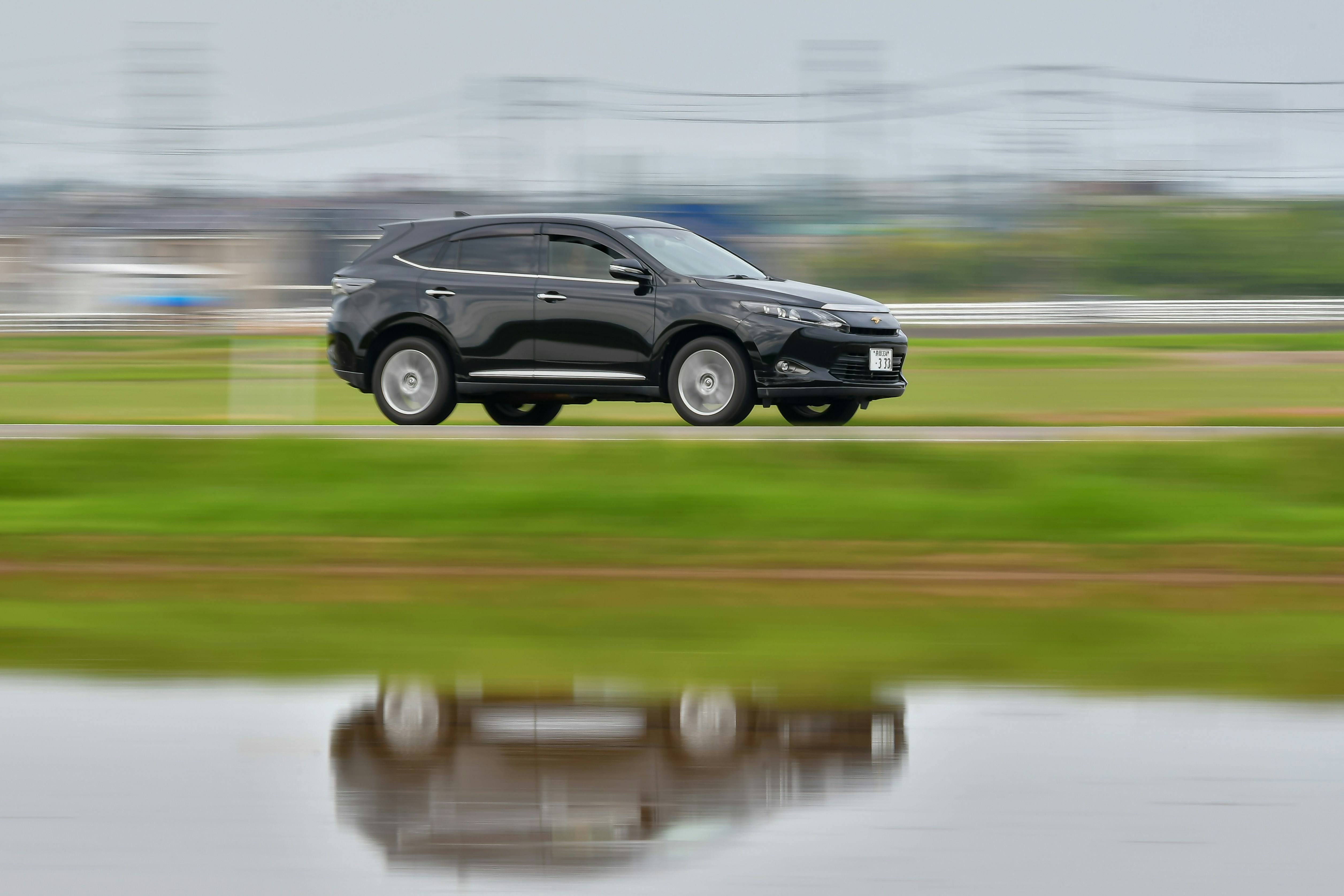 Ein schwarzer SUV fährt mit hoher Geschwindigkeit über ein Feld.