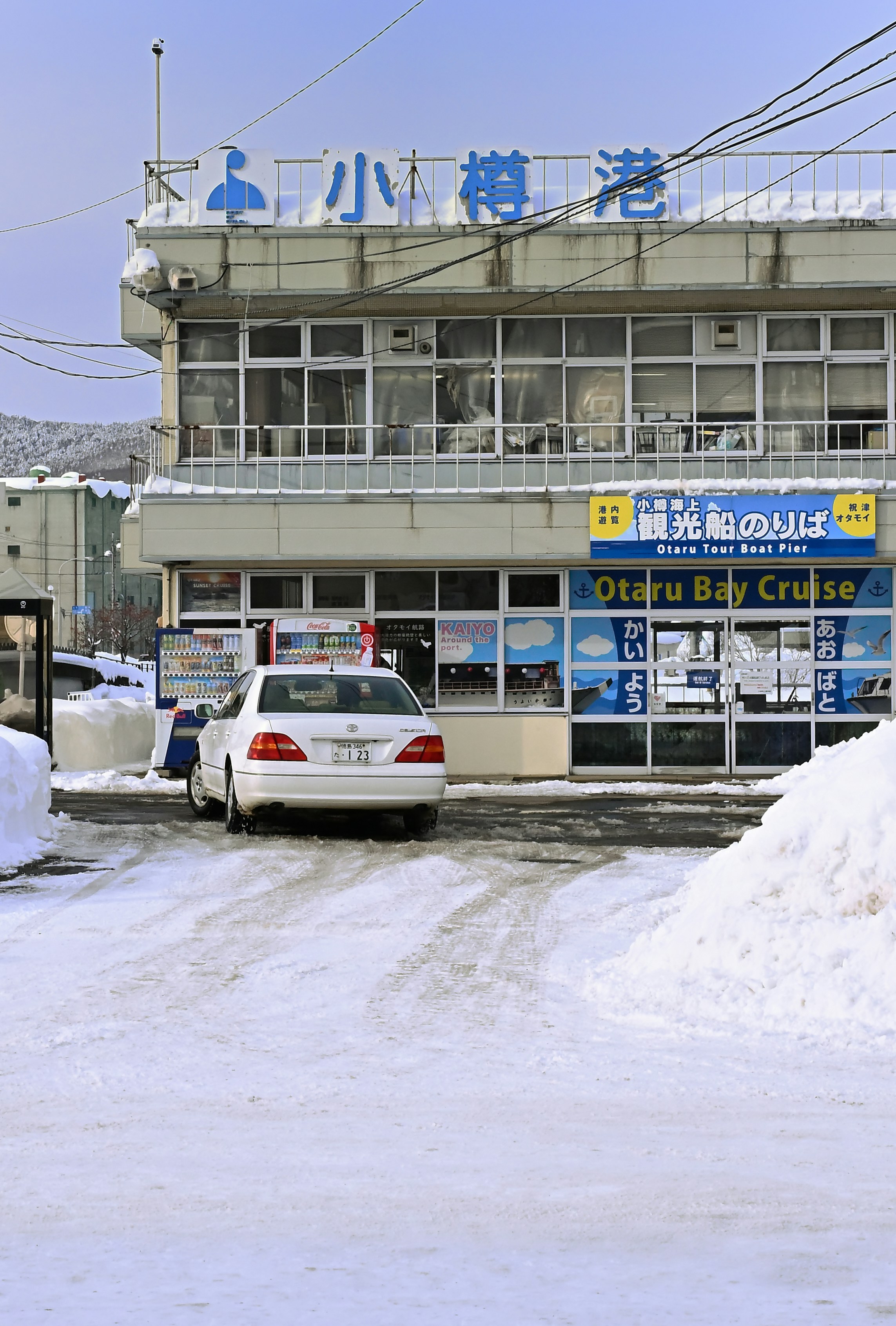 A car parks in front of a snowy ferry terminal.
