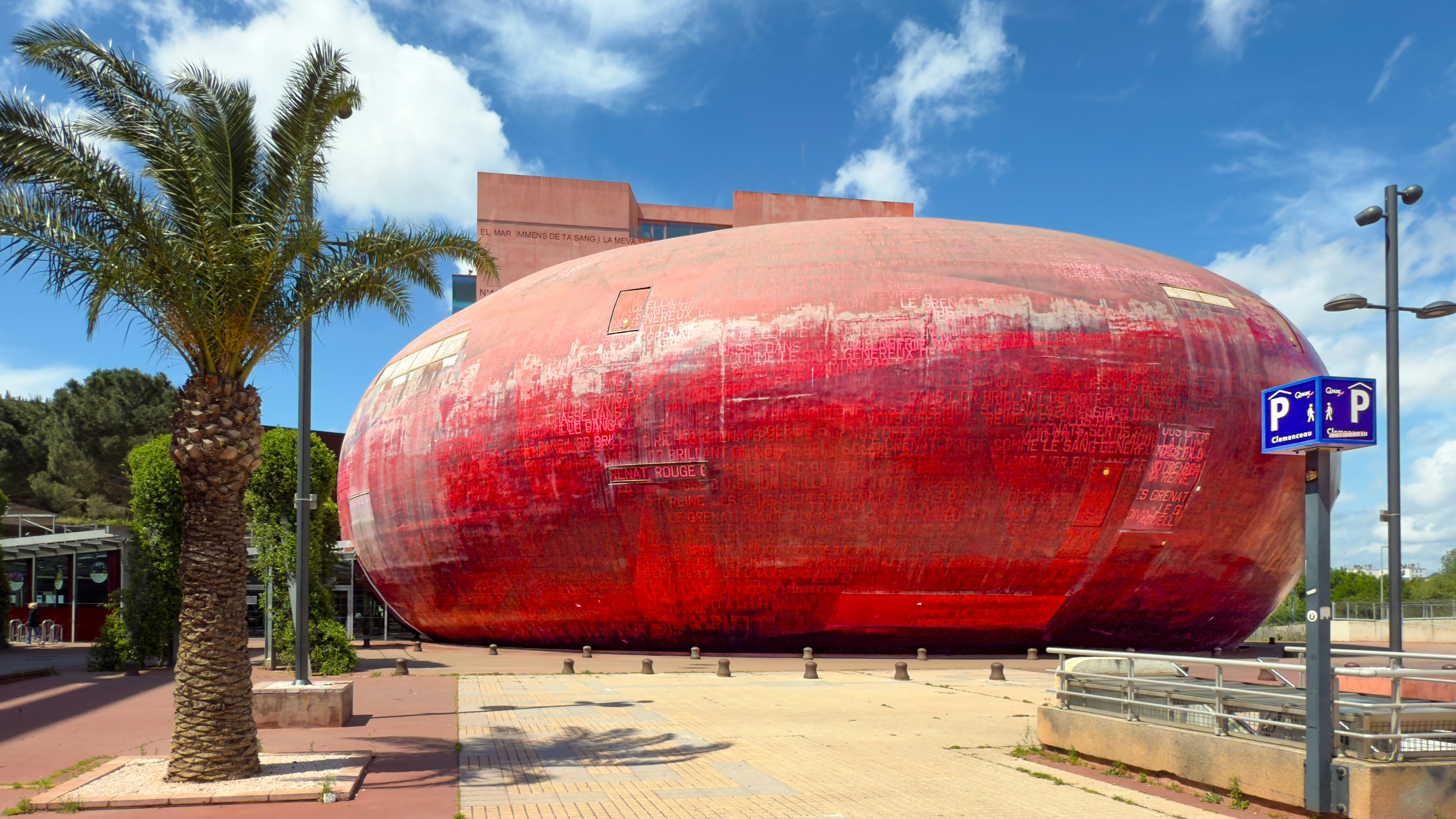 A striking red building sits under a bright sky.
