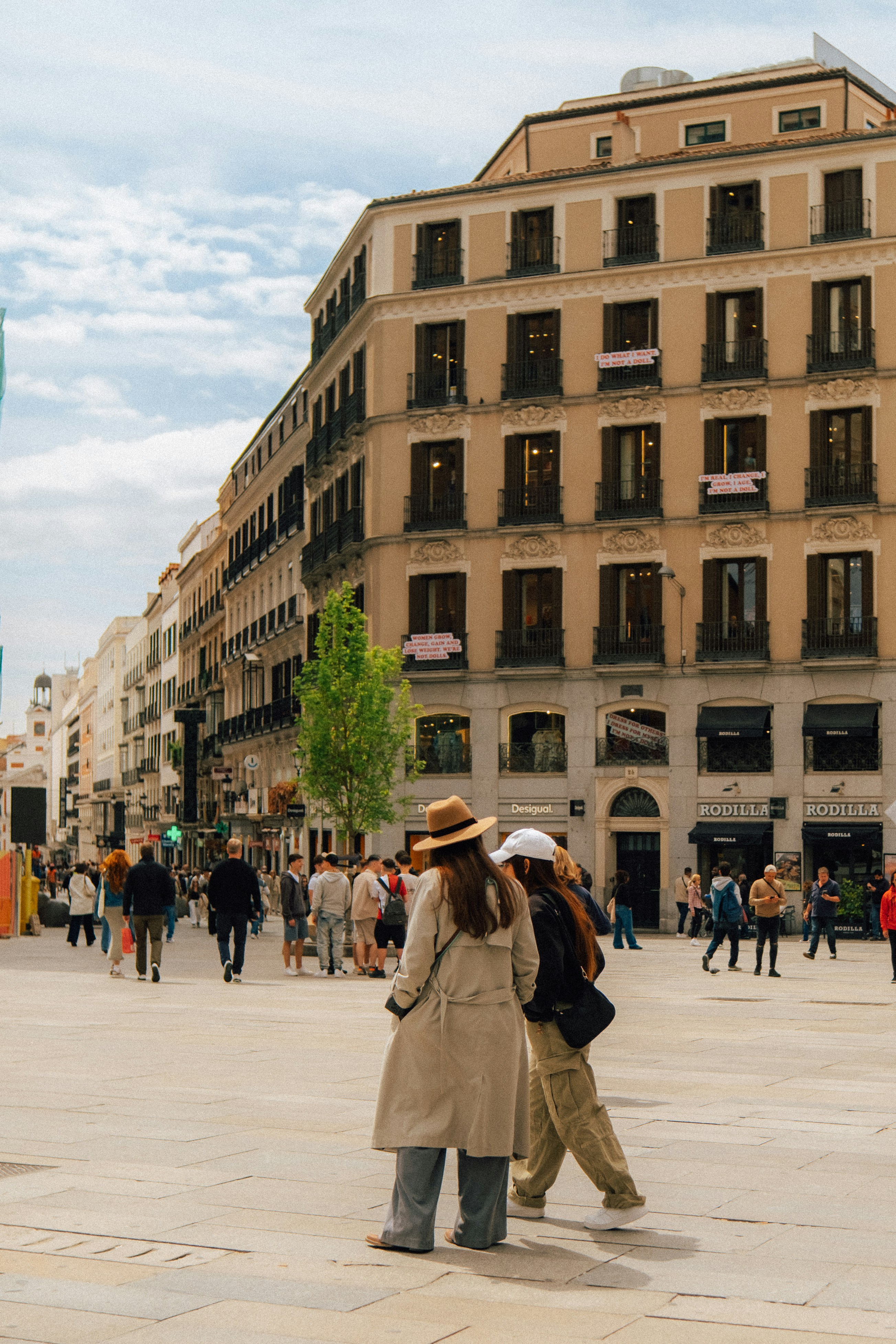 Two women walk through a bustling city square.