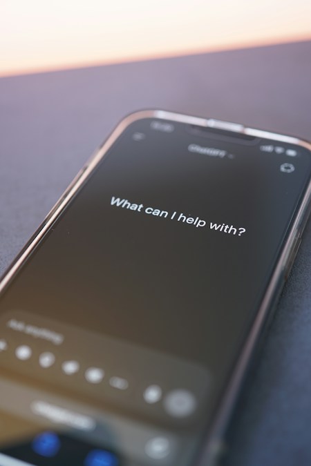Écran de smartphone affichant la question d’accueil d’un assistant d’IA, en illustration