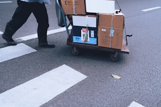 Person pulls a cart with boxes across a crosswalk.