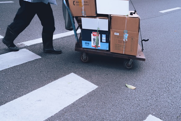 Person pulls a cart with boxes across a crosswalk.