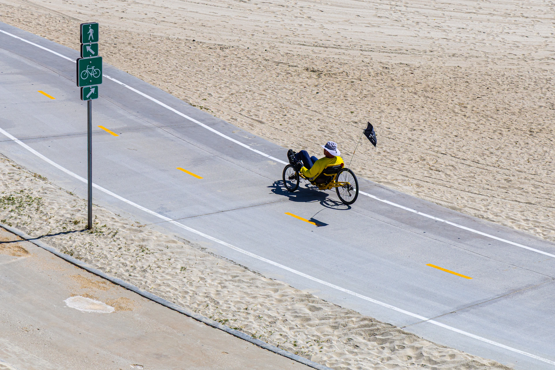 A cyclist rides on a road near a beach.