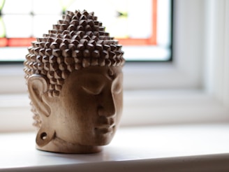 A buddha head statue sits on a windowsill.