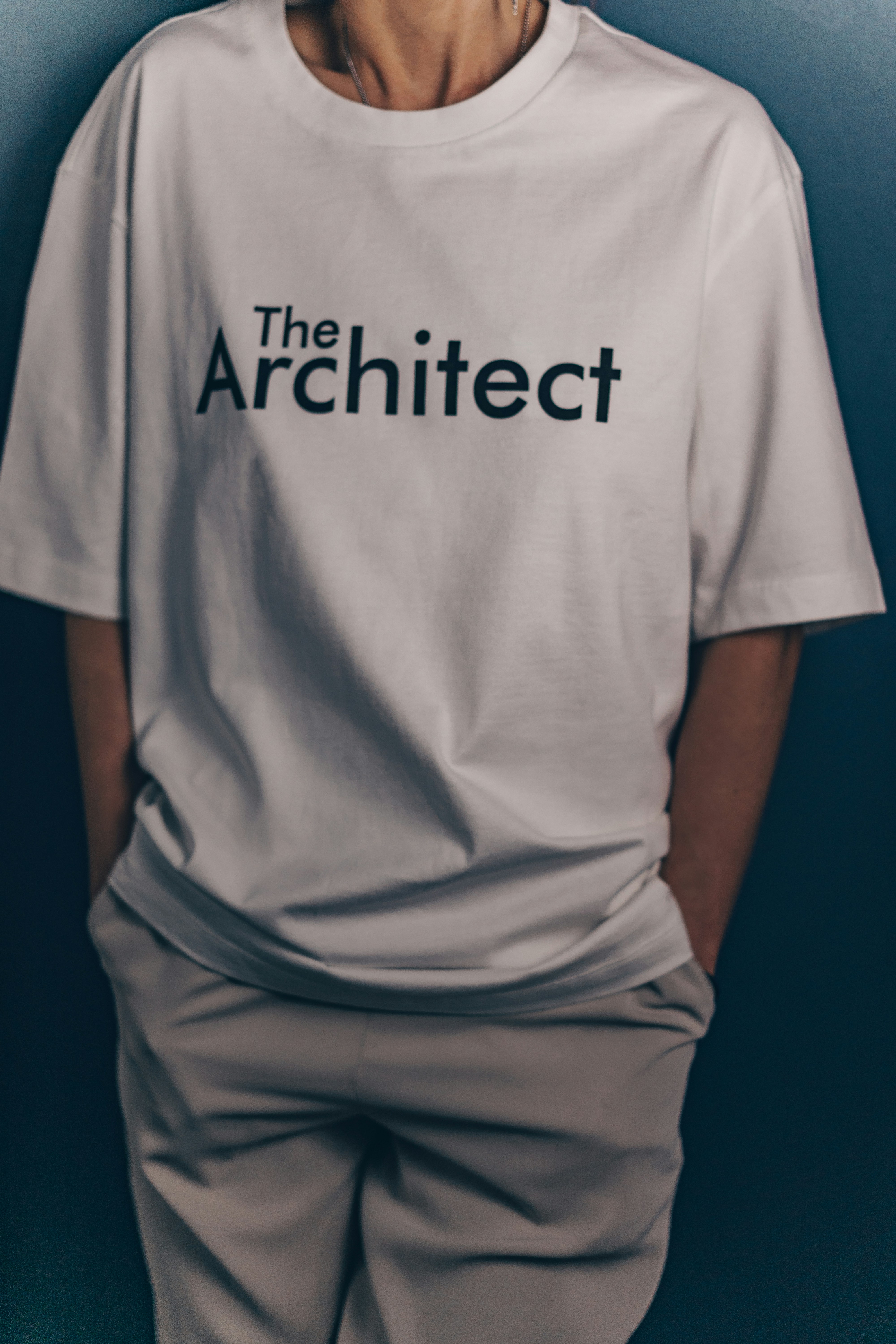 Someone wears a white "the architect" t-shirt.