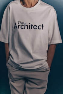 Someone wears a white "the architect" t-shirt.