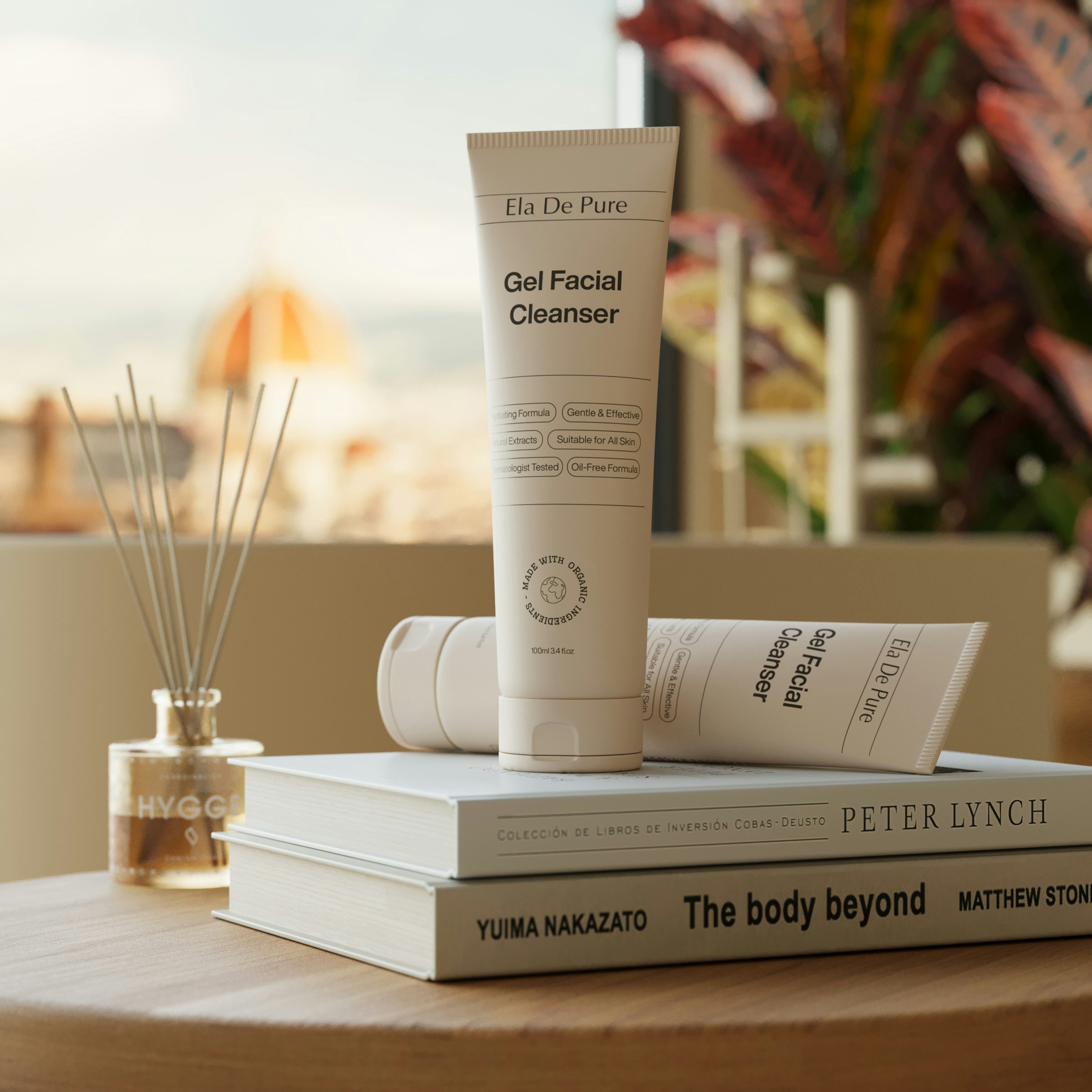 Skincare products are displayed on books in a nice setting.