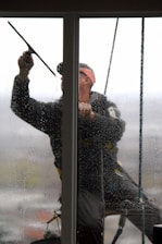 A window washer cleans a glass pane.