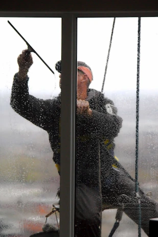 A window washer cleans a glass pane.