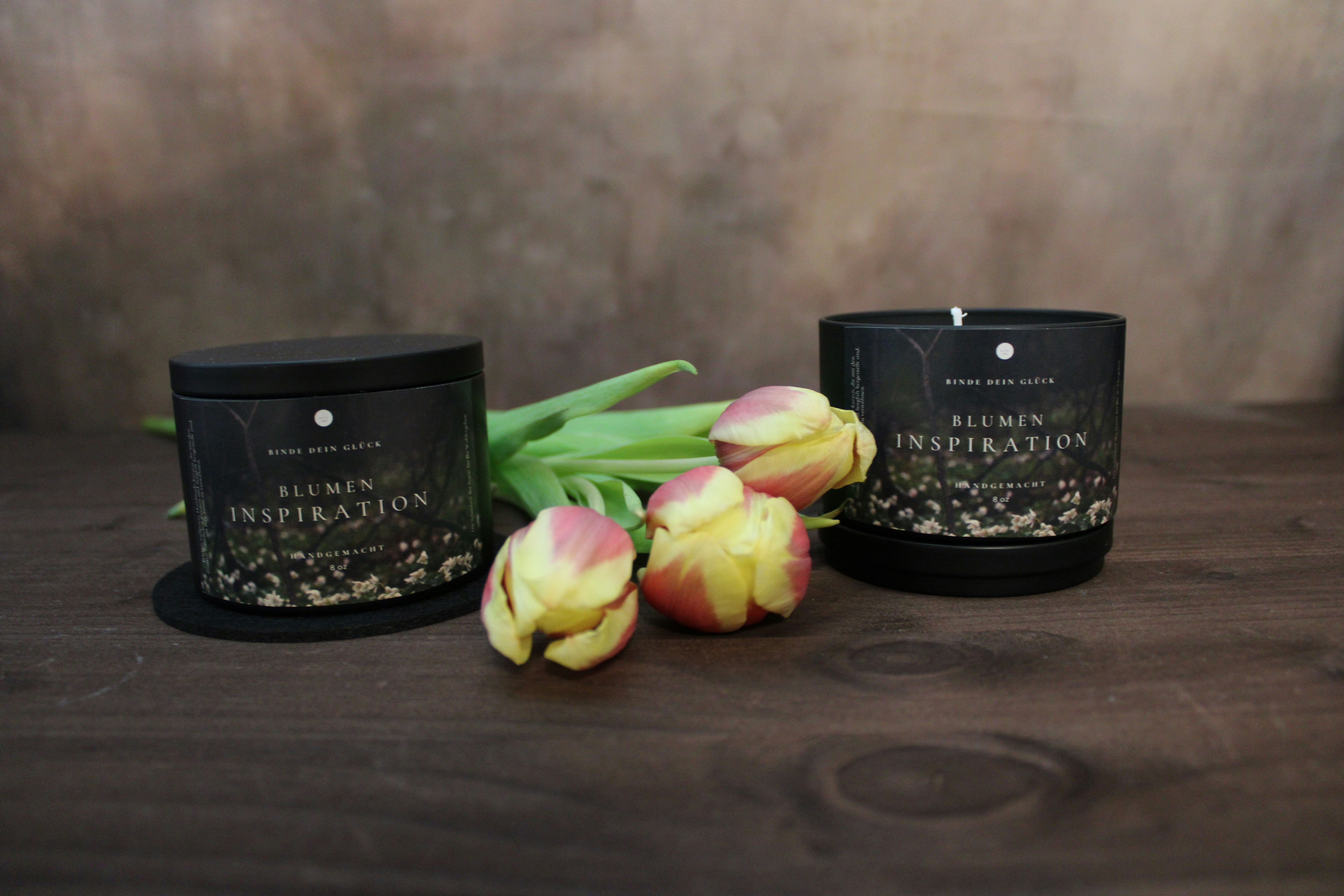 Candles and tulips sit on a wooden surface.