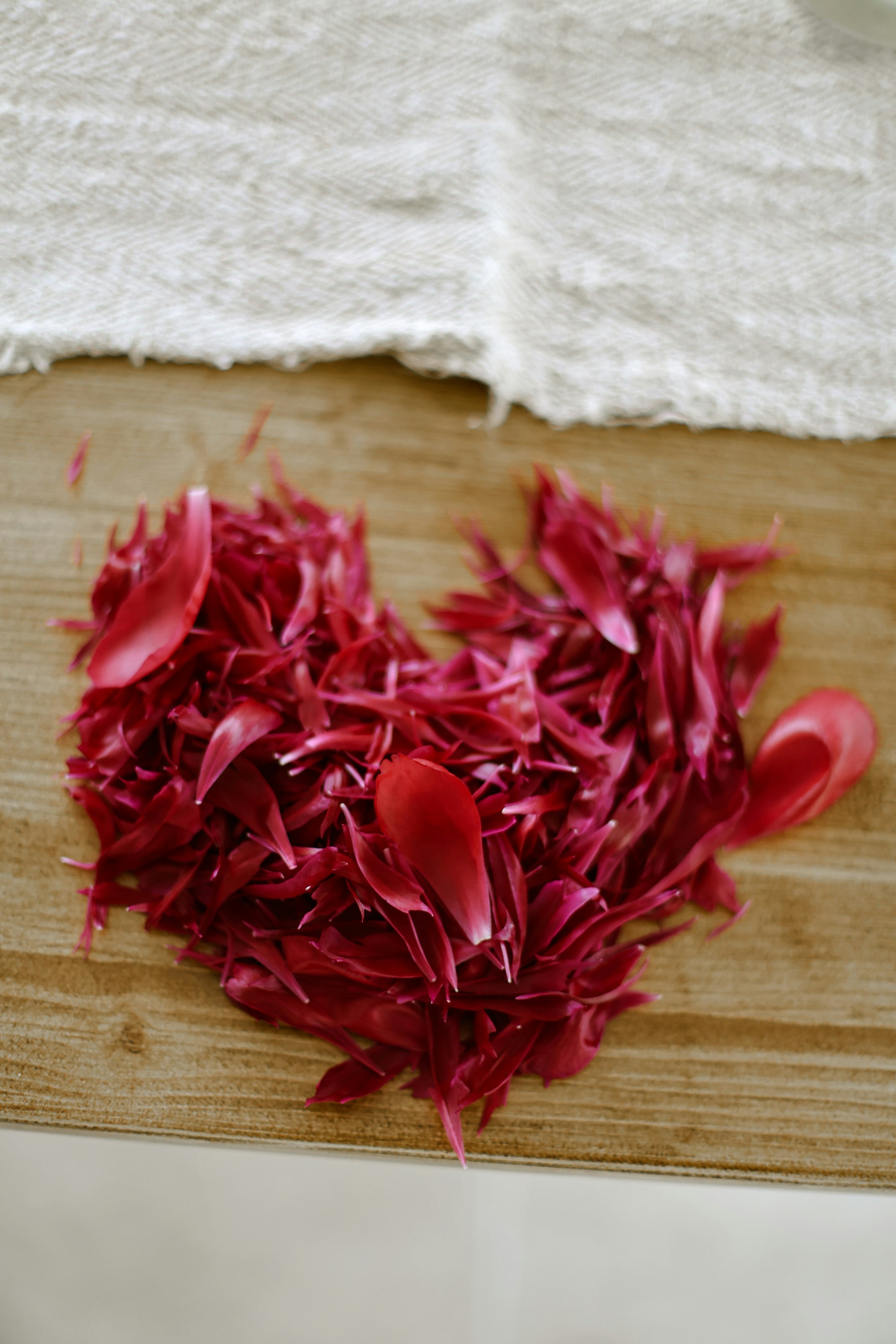 Red petals shaped into a heart on wood.