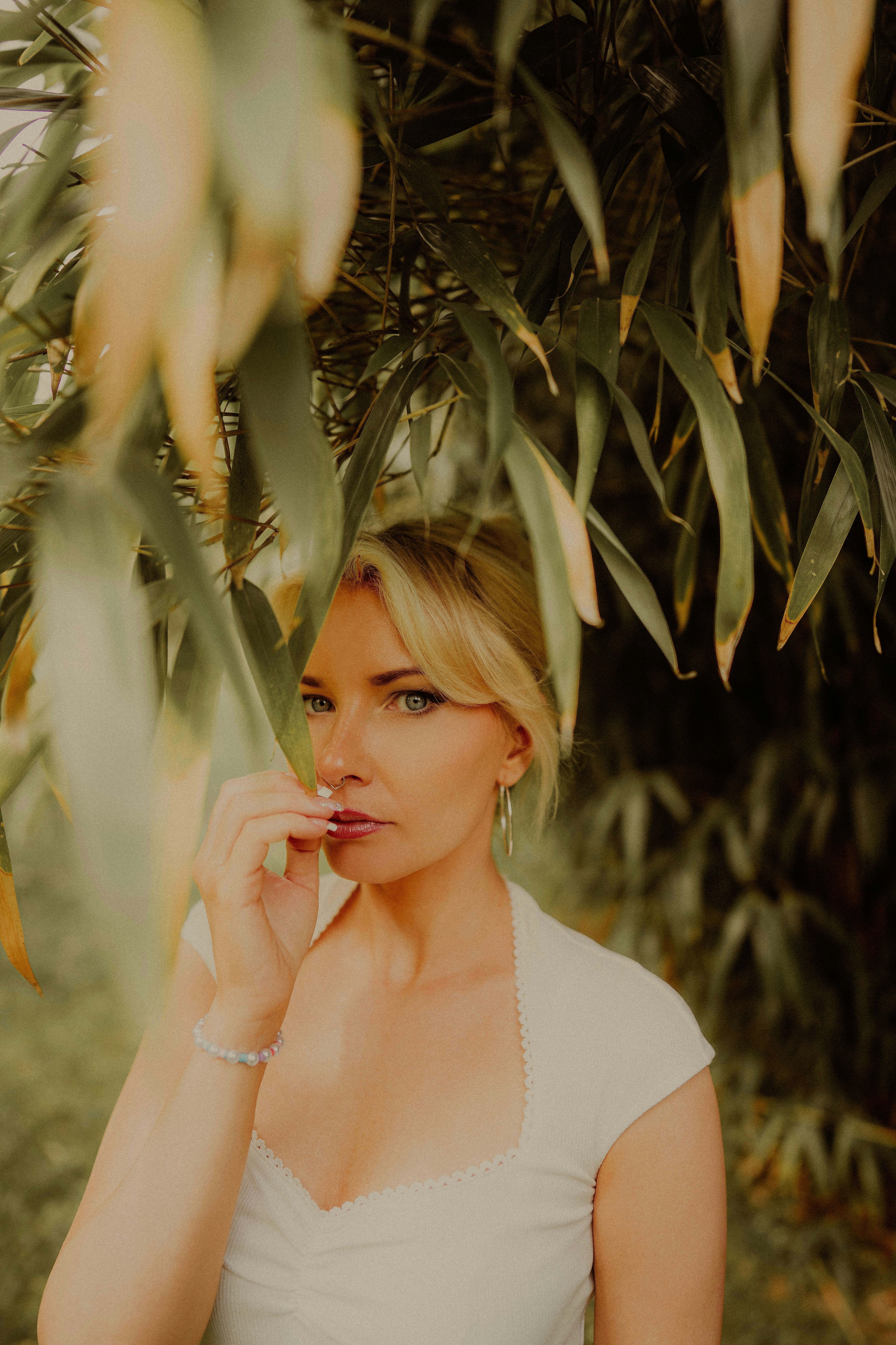 Blonde woman poses under bamboo leaves.