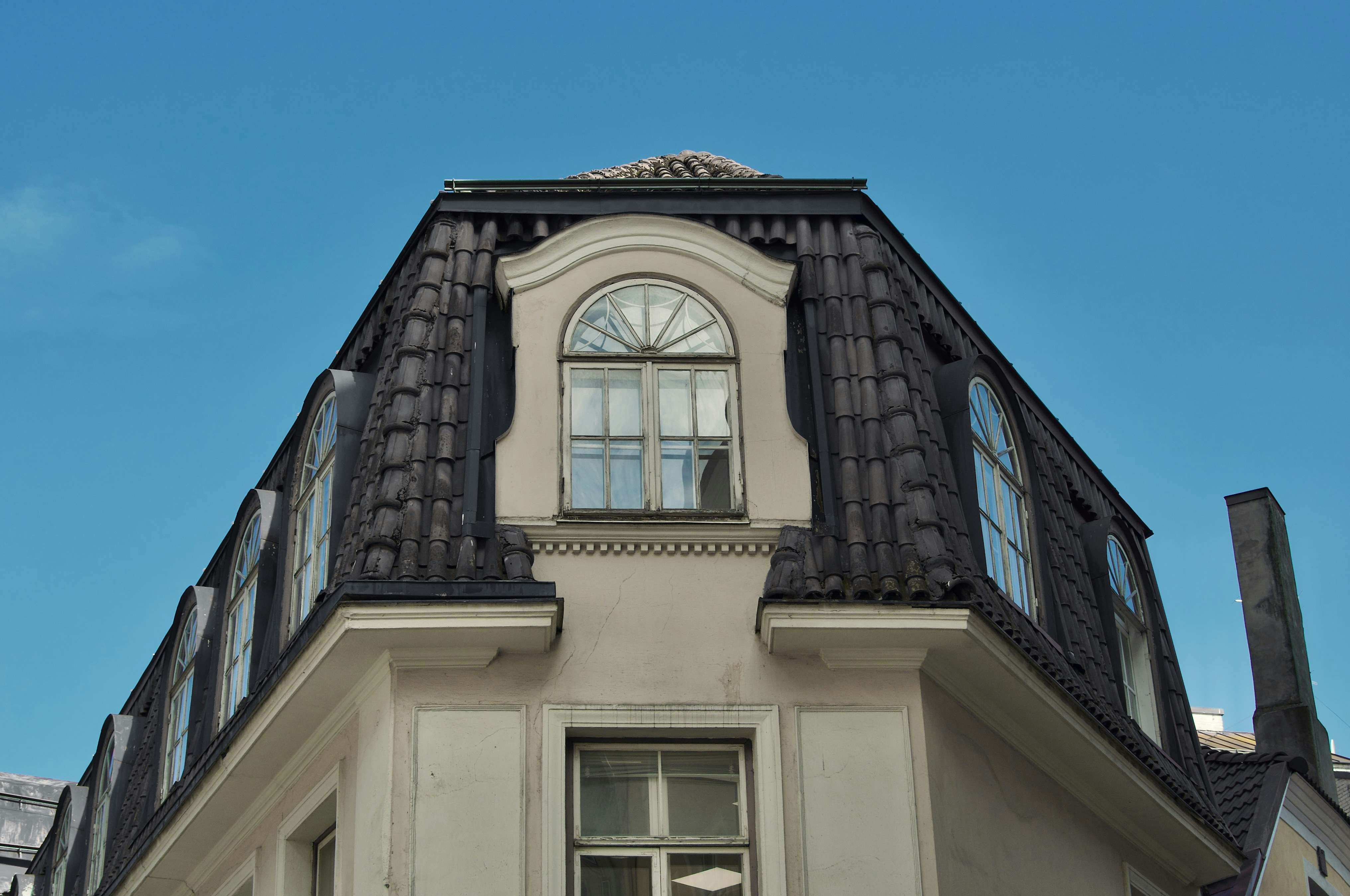 Un techo y ventanas contra un cielo azul brillante.