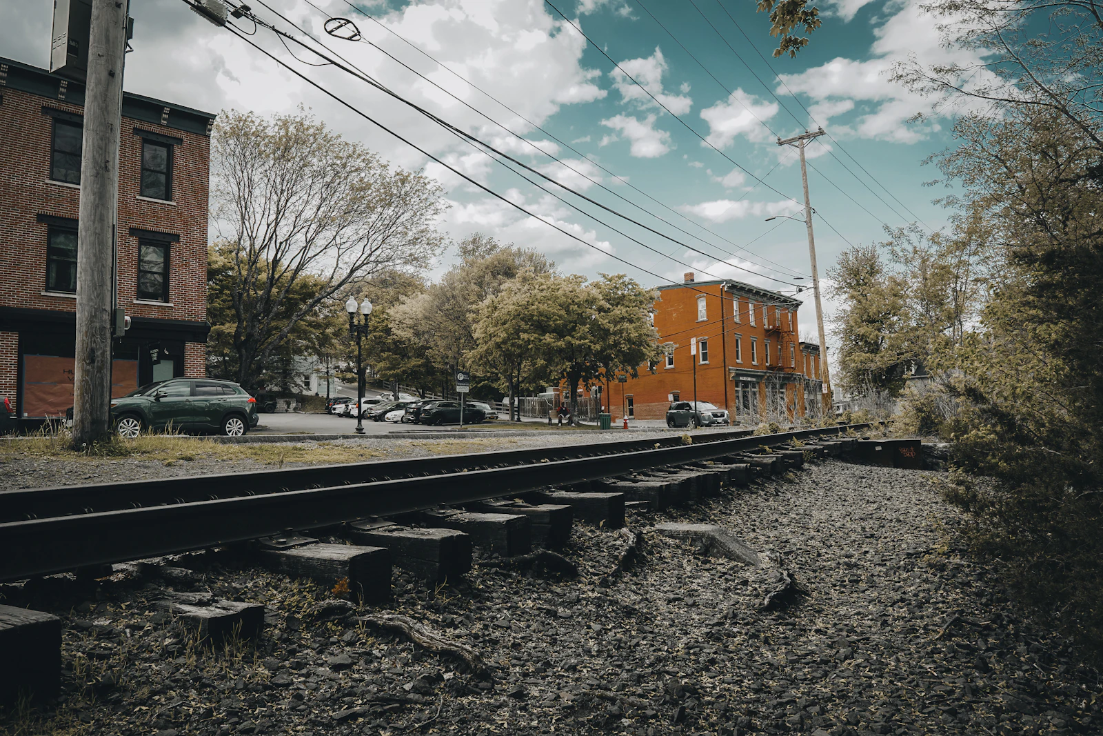 Railroad tracks running past brick buildings in a small town.