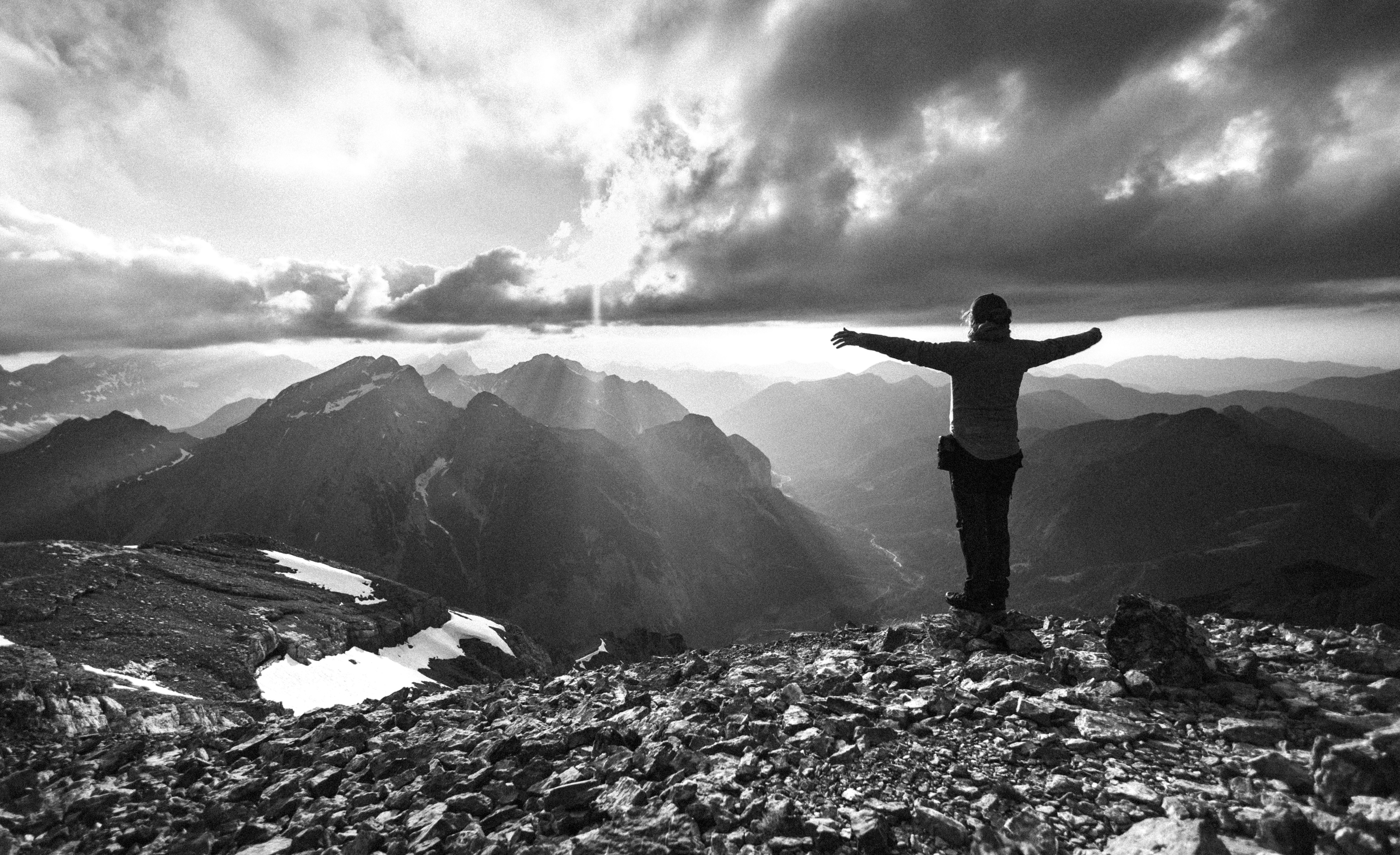 A person celebrates victory on top of a mountain.