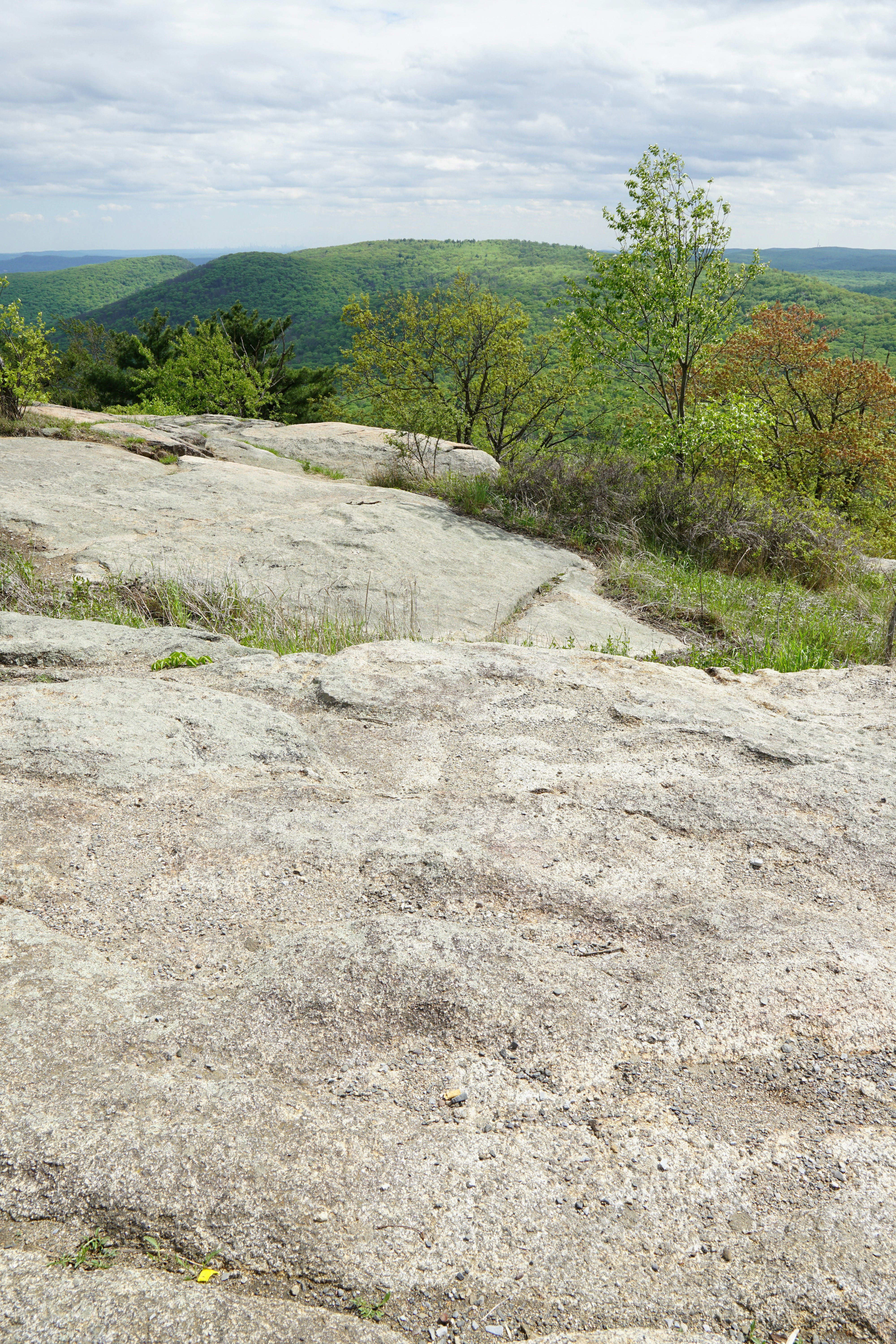 Rocky landscape overlooks lush green hills.