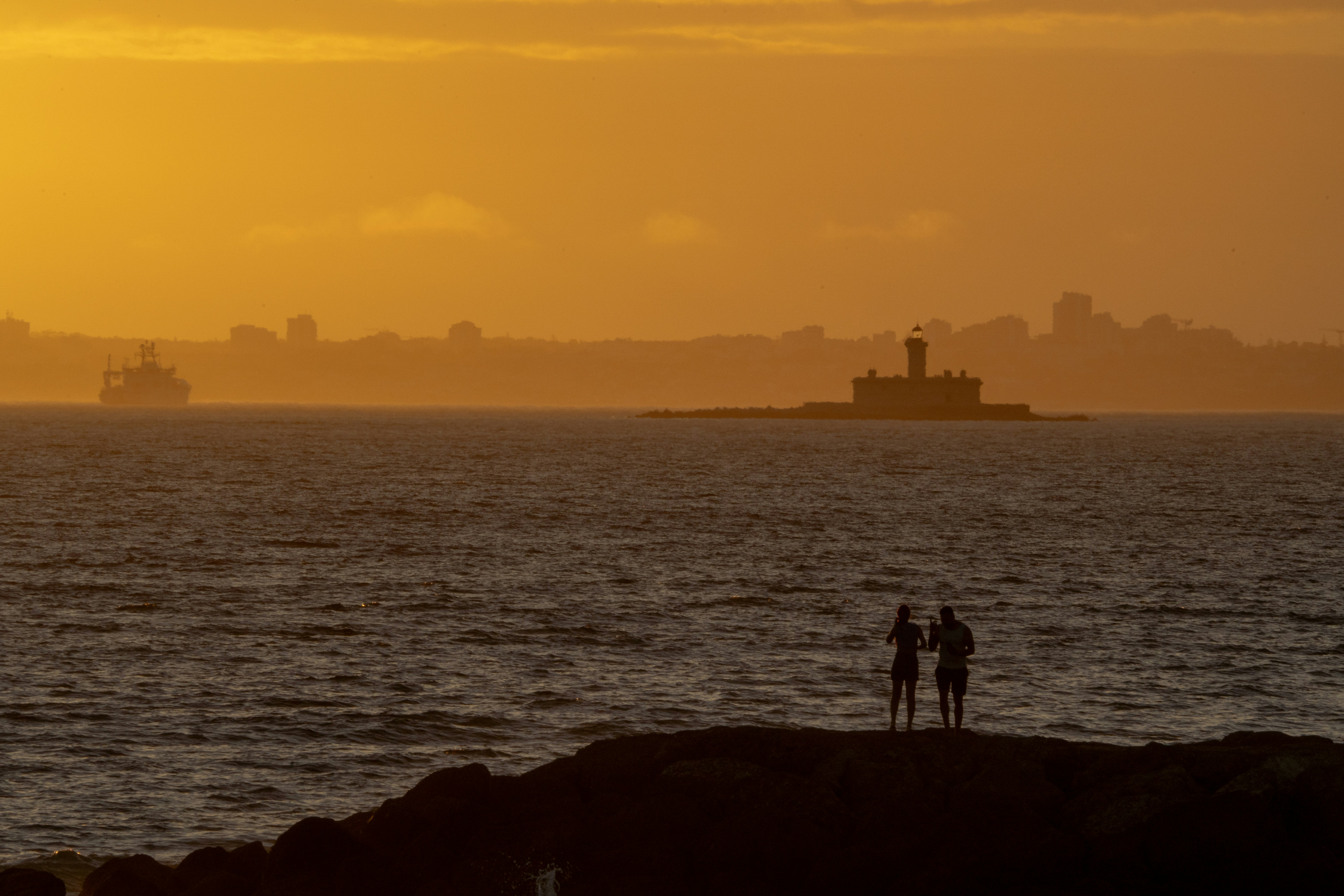 Les gens regardent le coucher de soleil sur l’océan.