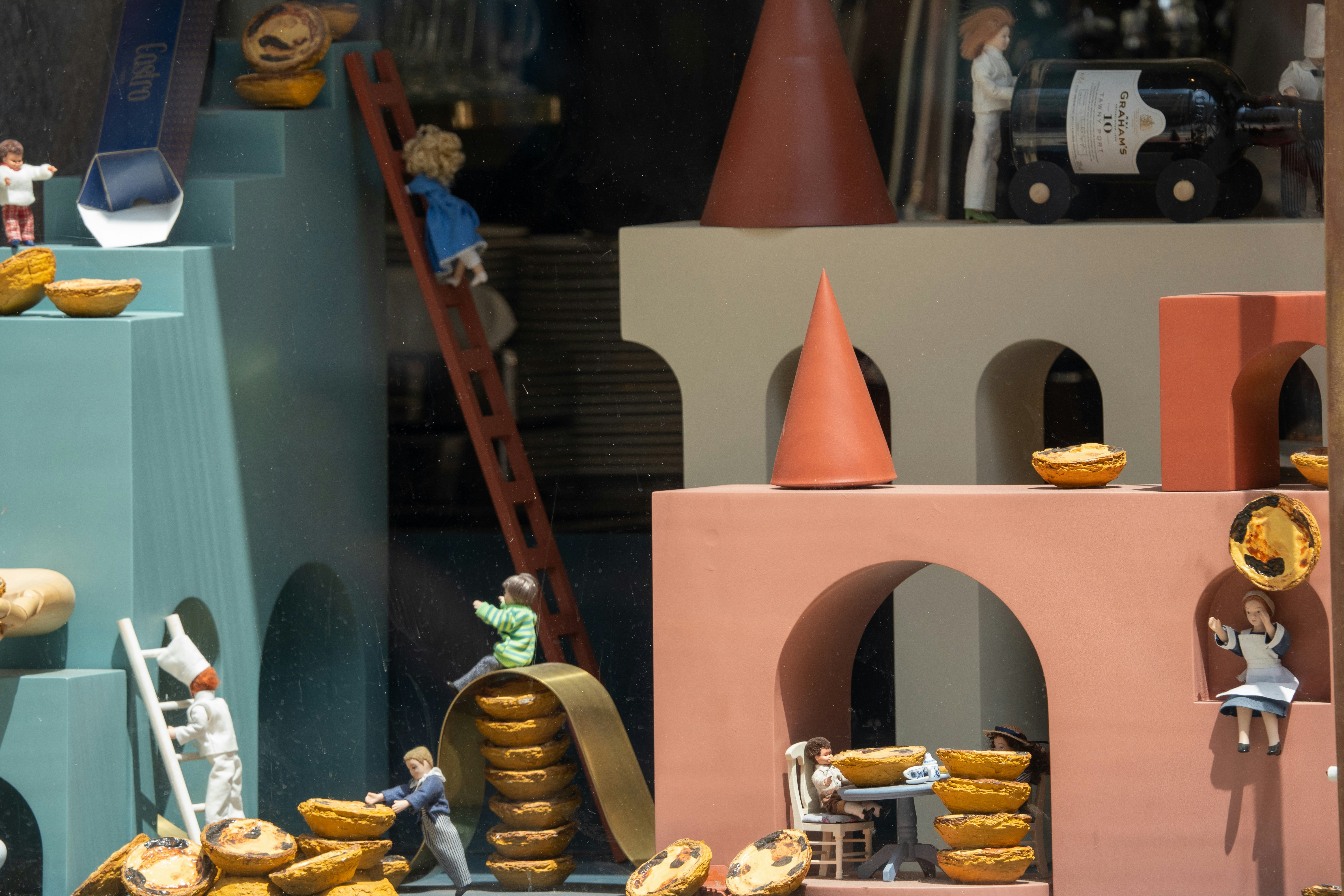 Des figures miniatures interagissent avec des structures architecturales colorées.