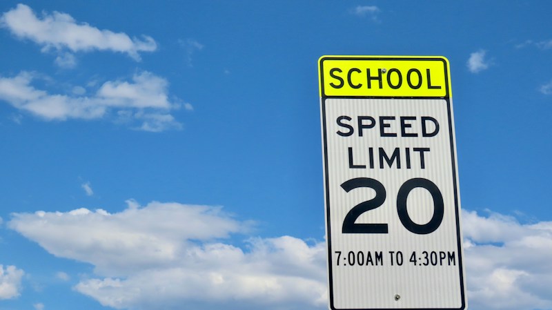 School zone speed limit sign against a cloudy sky, a reminder that Nevada doubled school zone fines in 2026