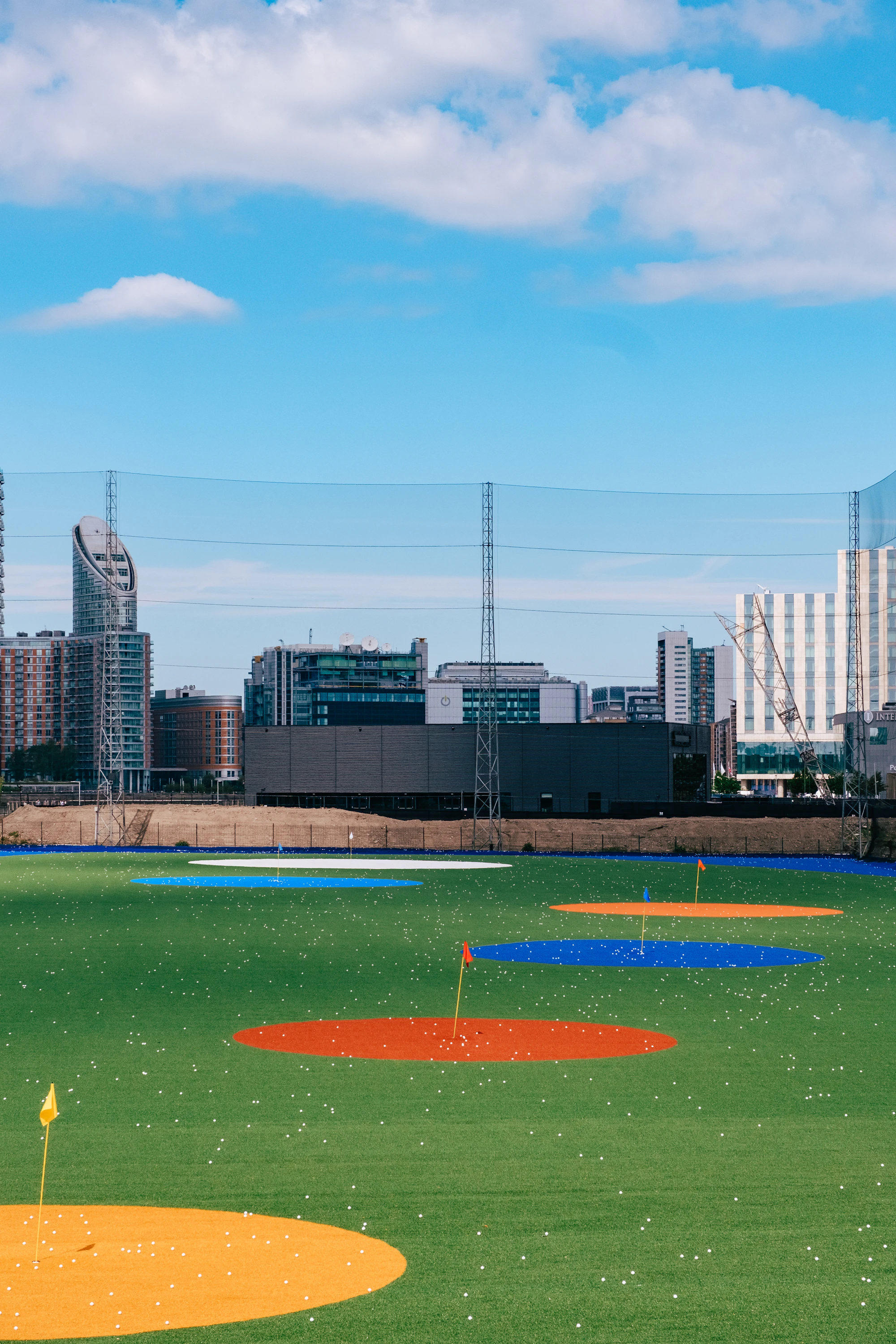 Golfers hitting from a city driving range toward the fairway nets