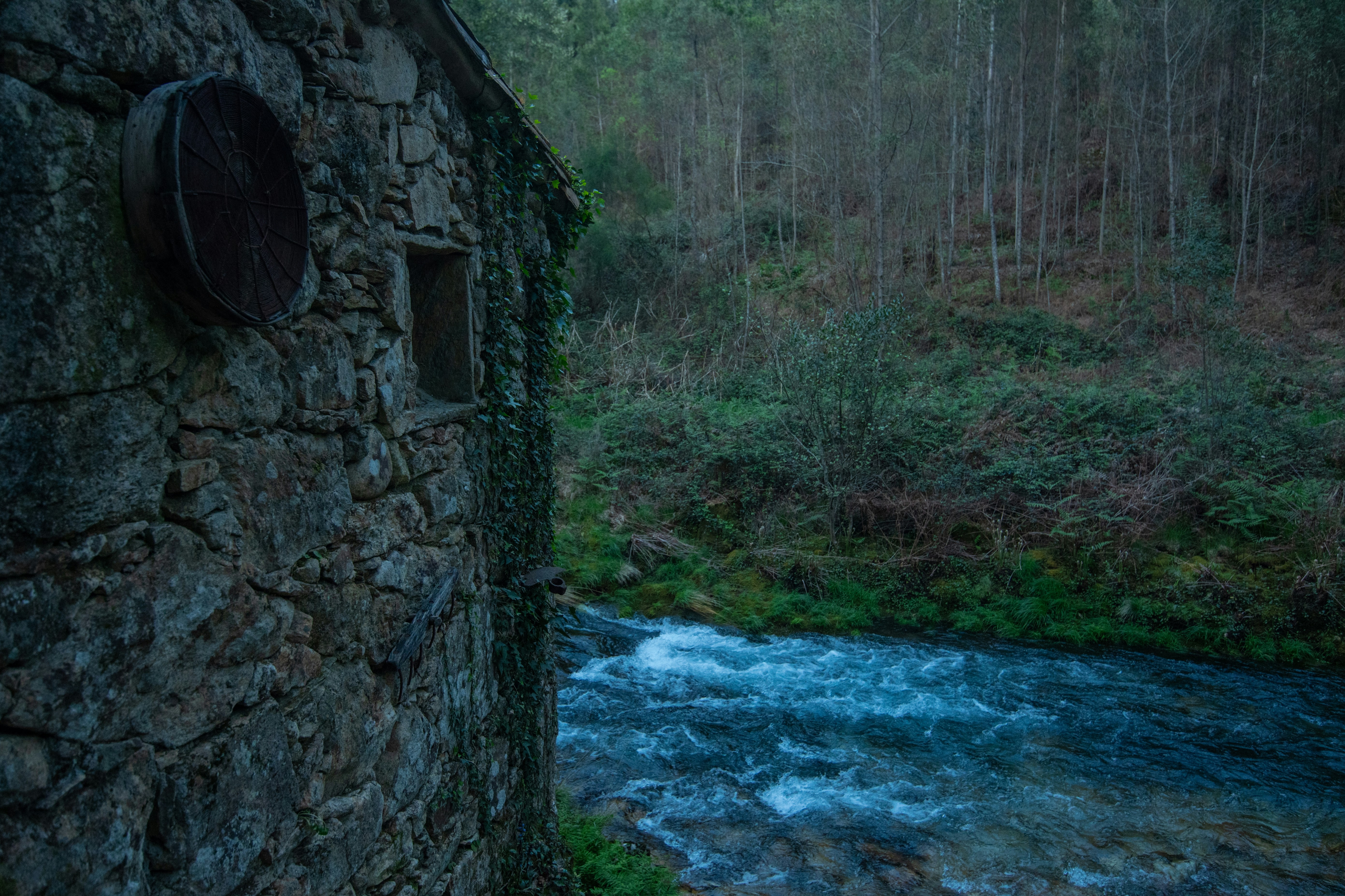 An old stone building sits near a flowing river.