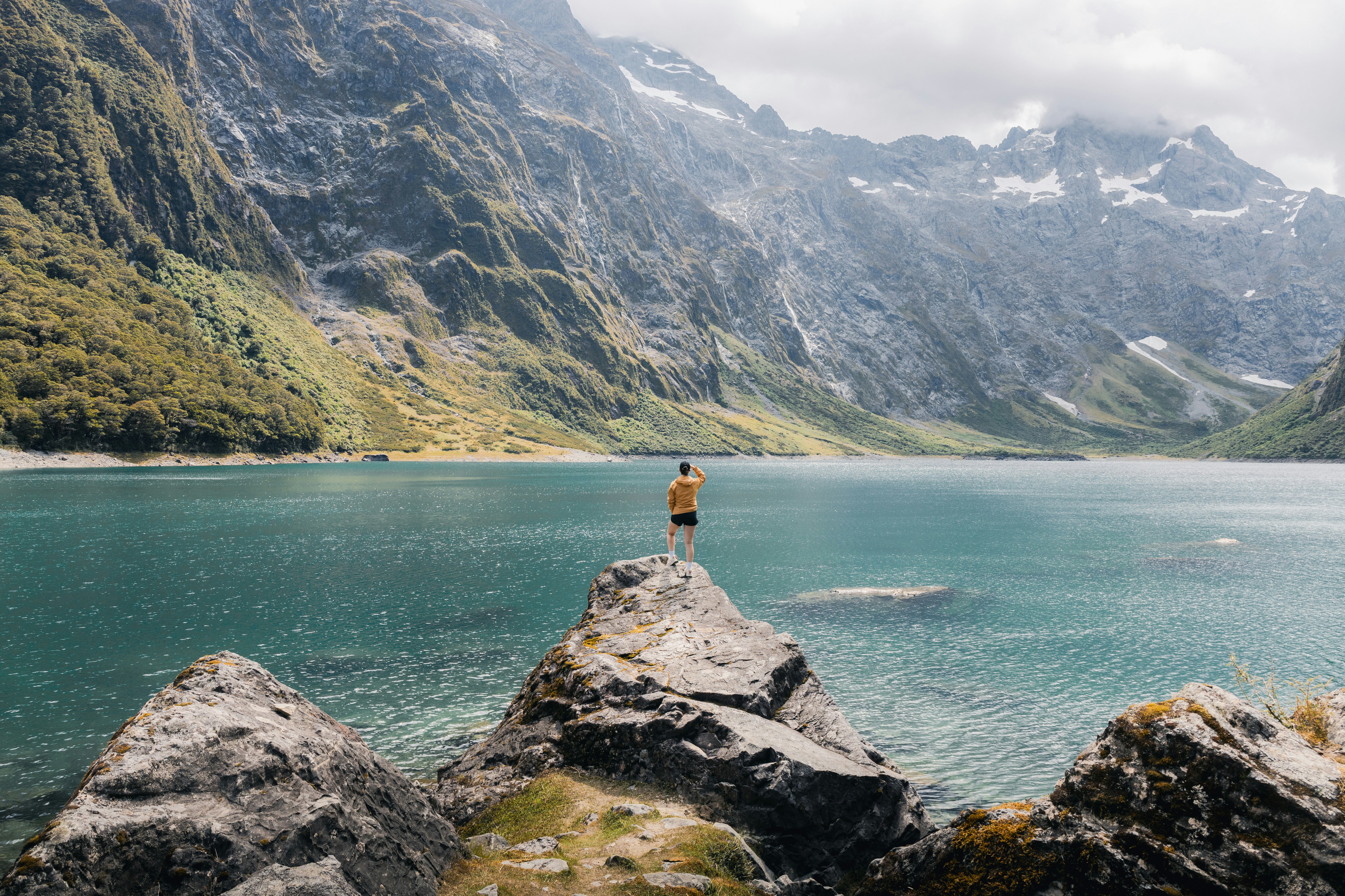 La persona disfruta de una impresionante vista del lago y las montañas.