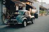 An antique car sits parked on a cobblestone street.