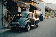 An antique car sits parked on a cobblestone street.