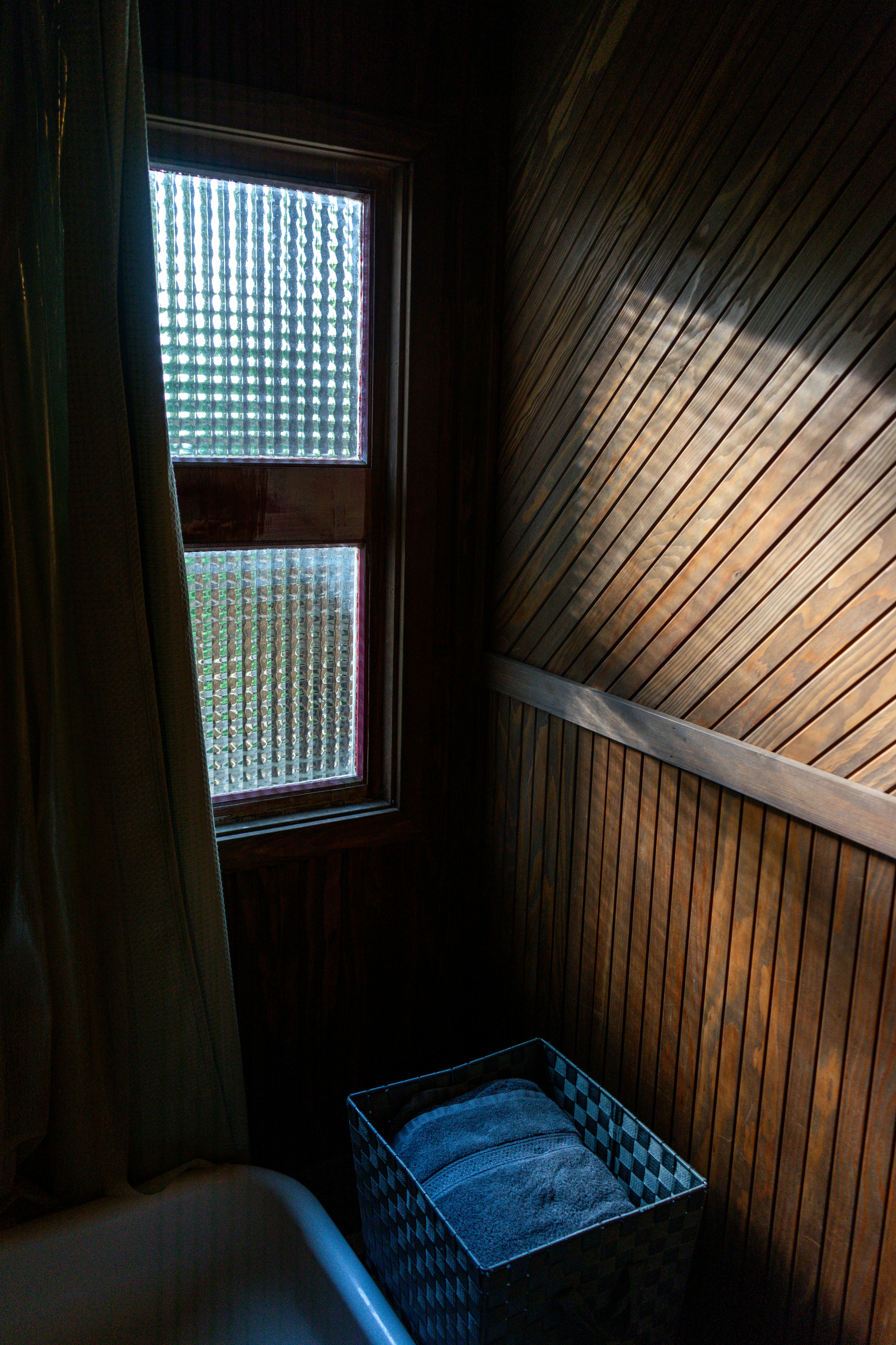 Light shines into a cozy, wood-paneled bathroom.