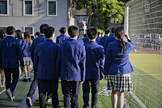 Students in uniform are walking near a sports field