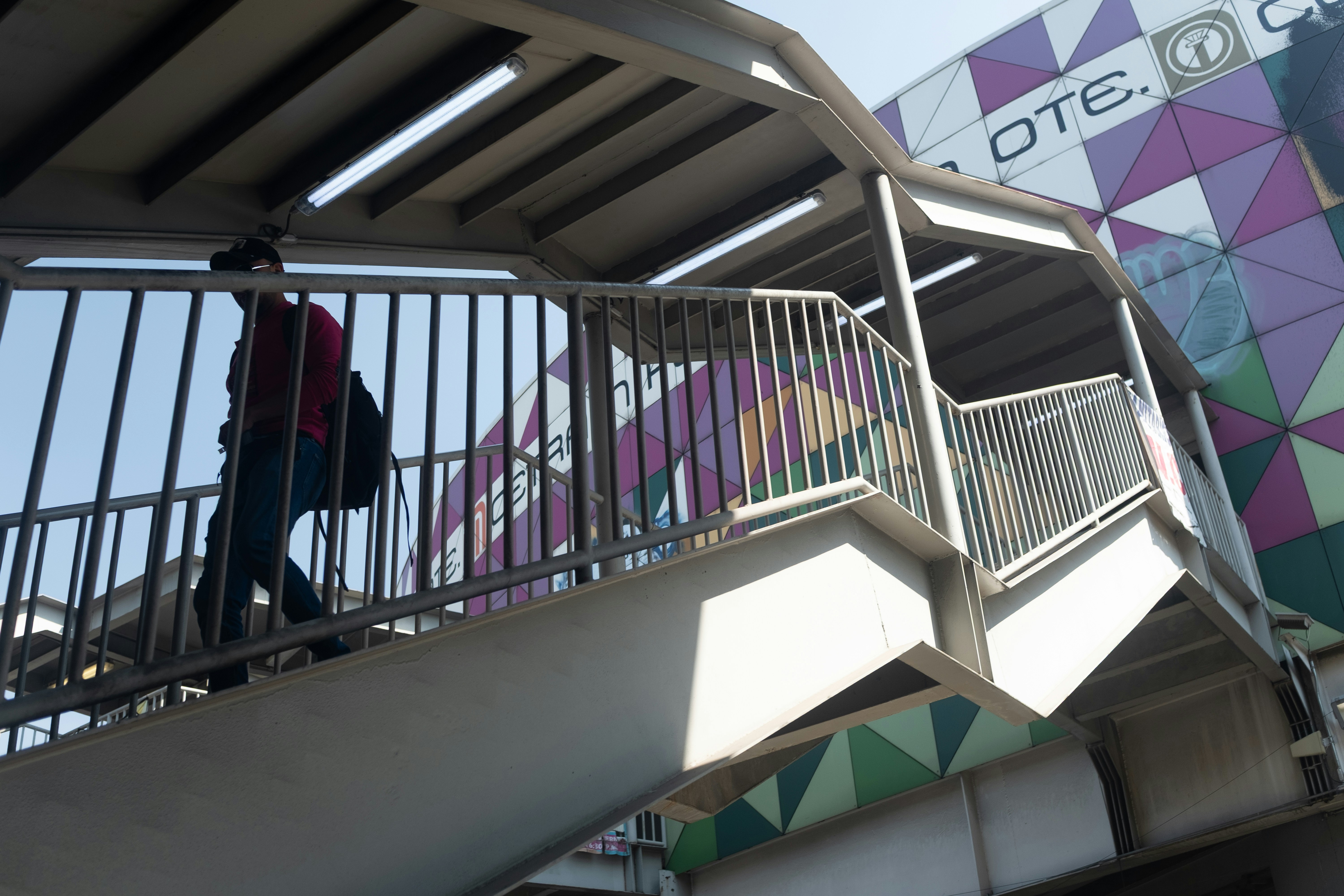A person walks up stairs of a pedestrian bridge.