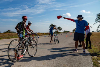Cyclists line up as official waves the starting flag.