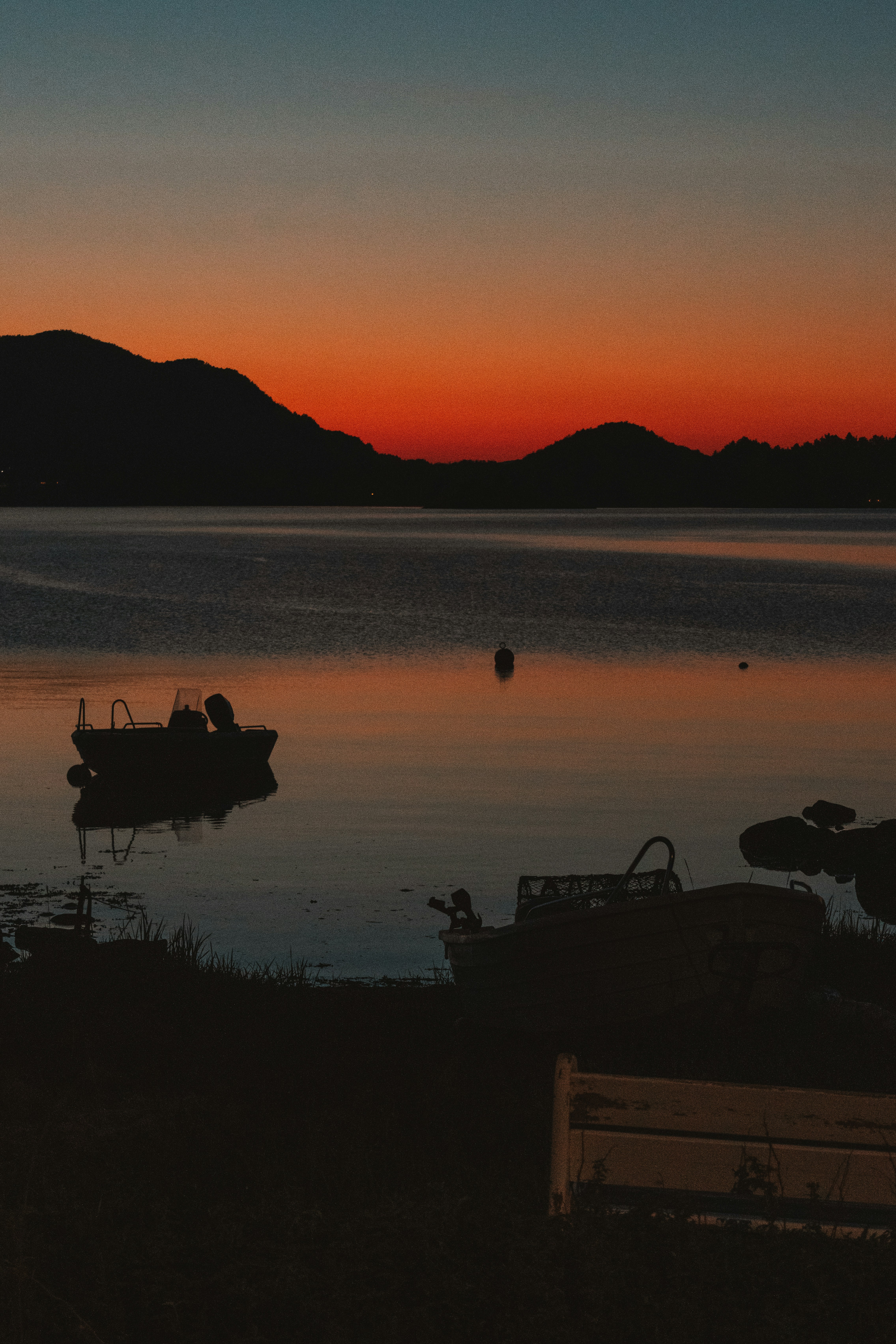 Sunset silhouettes boats on a tranquil lake.