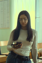 A woman holds glasses, looking down.