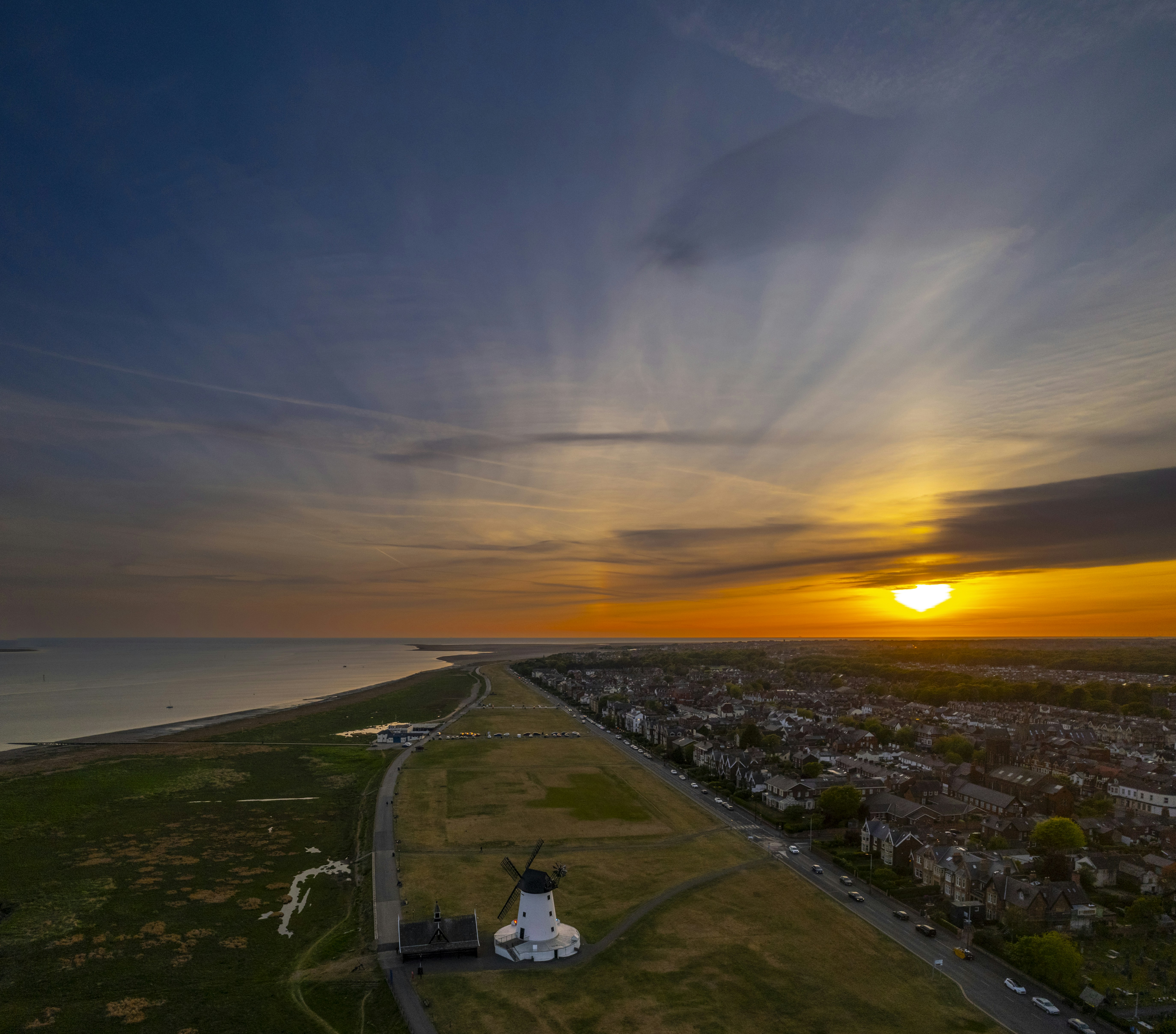 Sunset bathes a windmill and landscape in golden light.