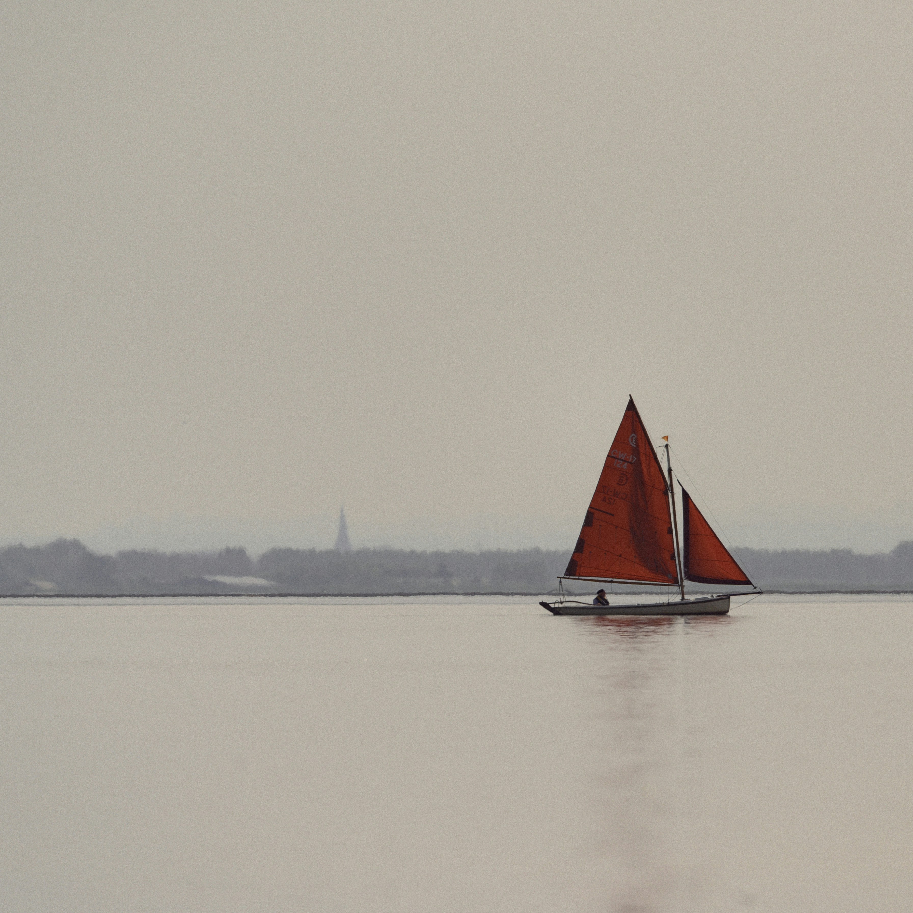 A sailboat with red sails glides peacefully.