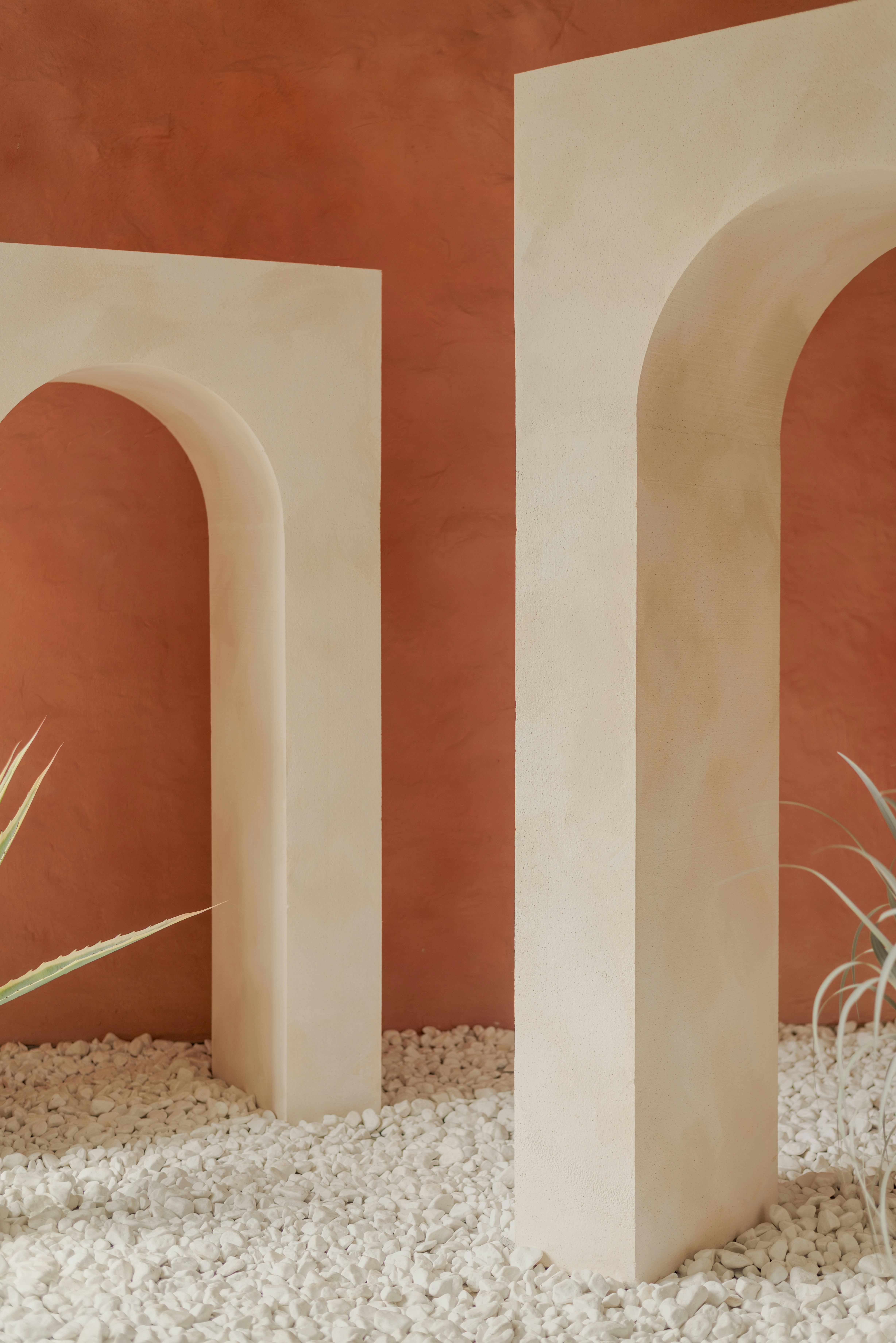 Arches stand on a bed of pebbles against an orange wall