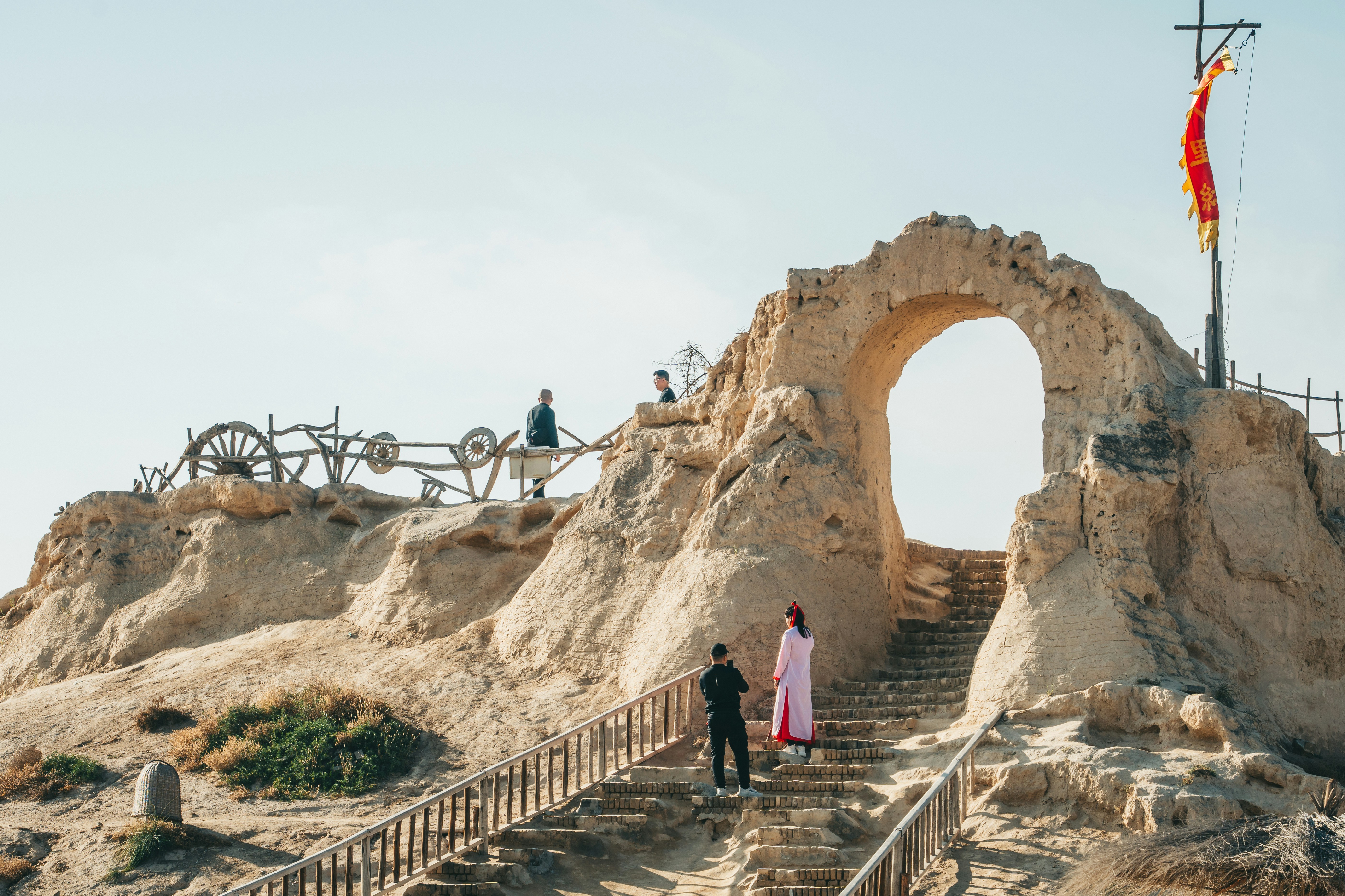 People ascend a stone staircase towards a scenic archway.