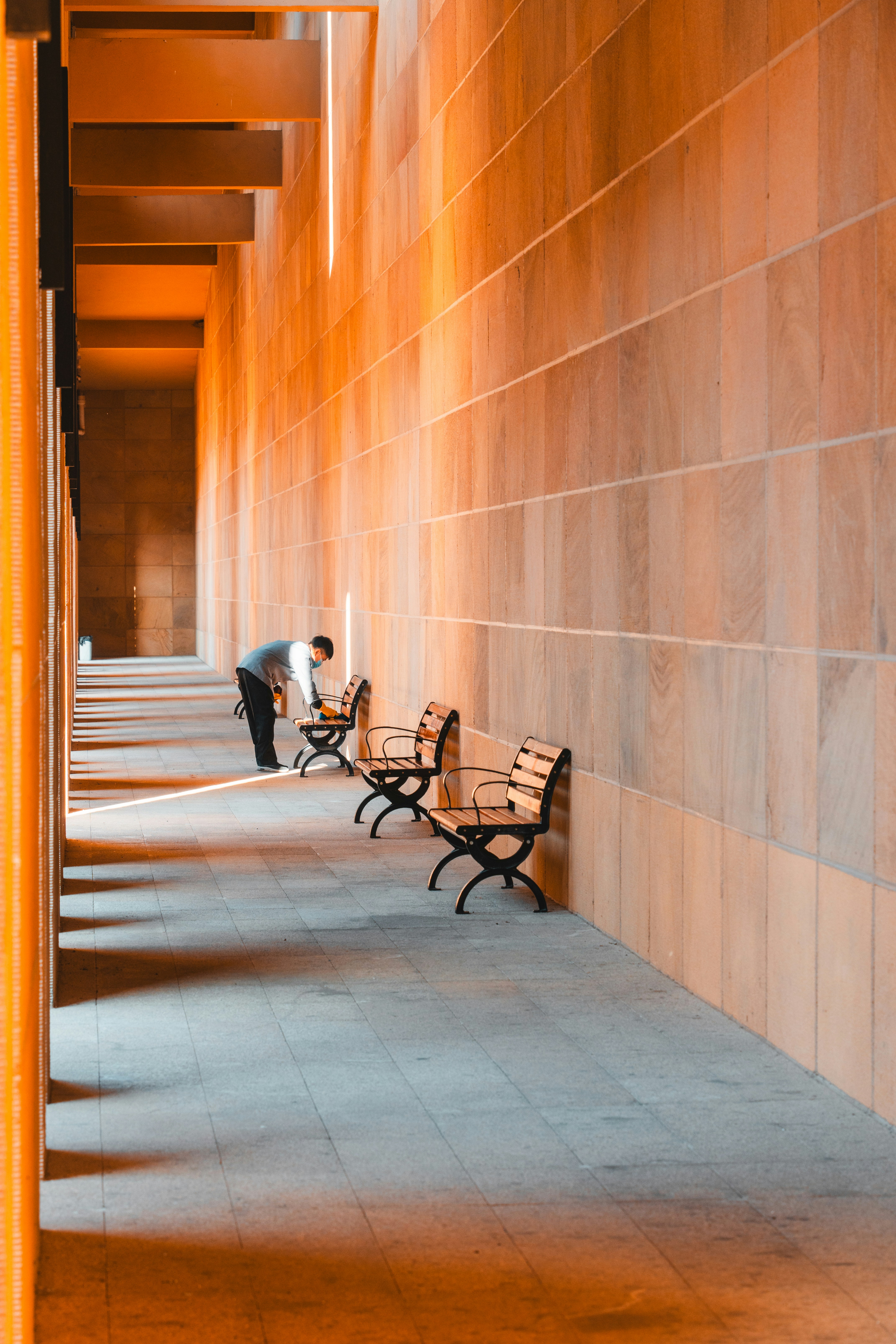 A person tends to chairs in a long, bright corridor.