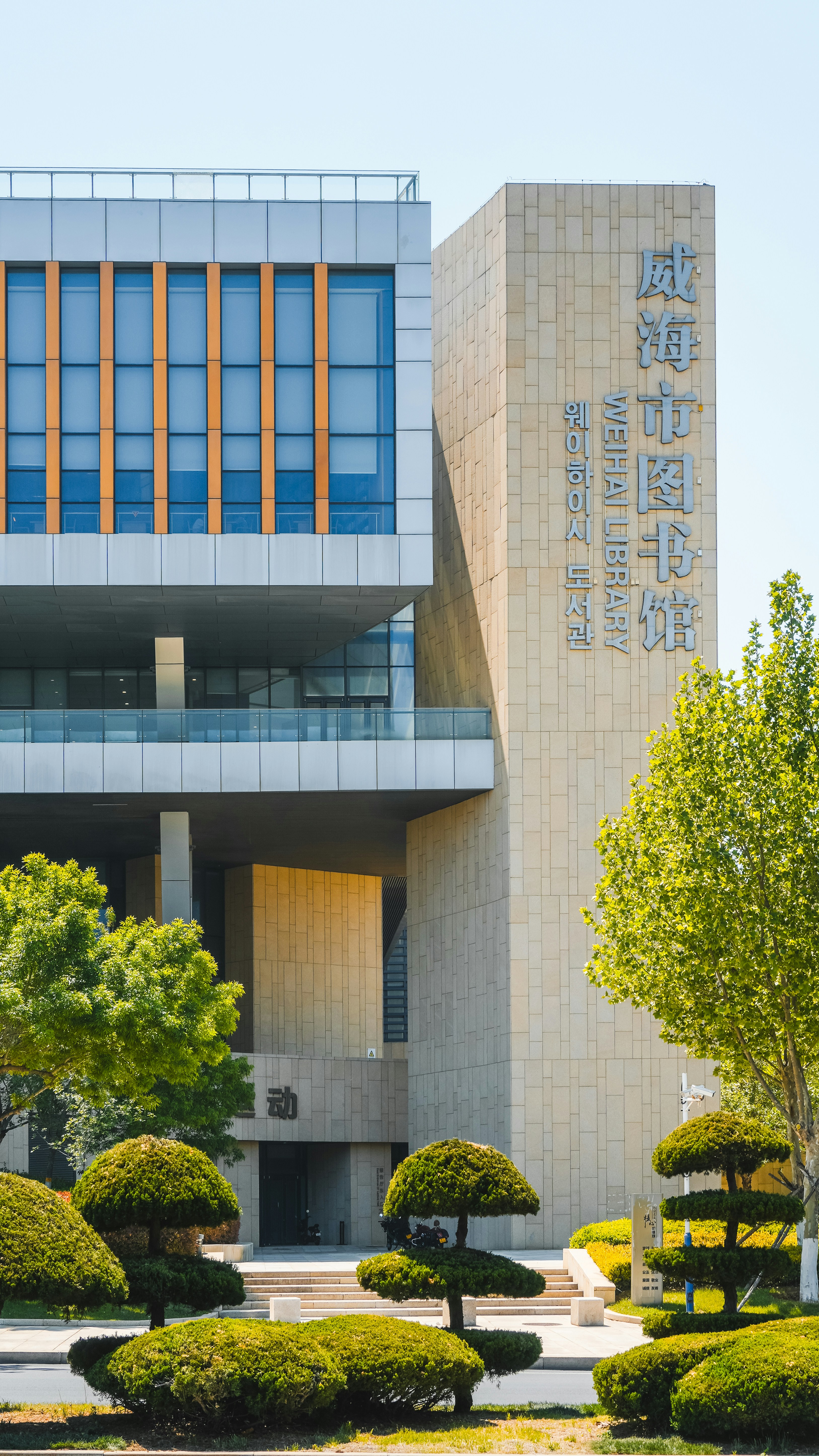 The weihai library stands tall with lush landscaping.