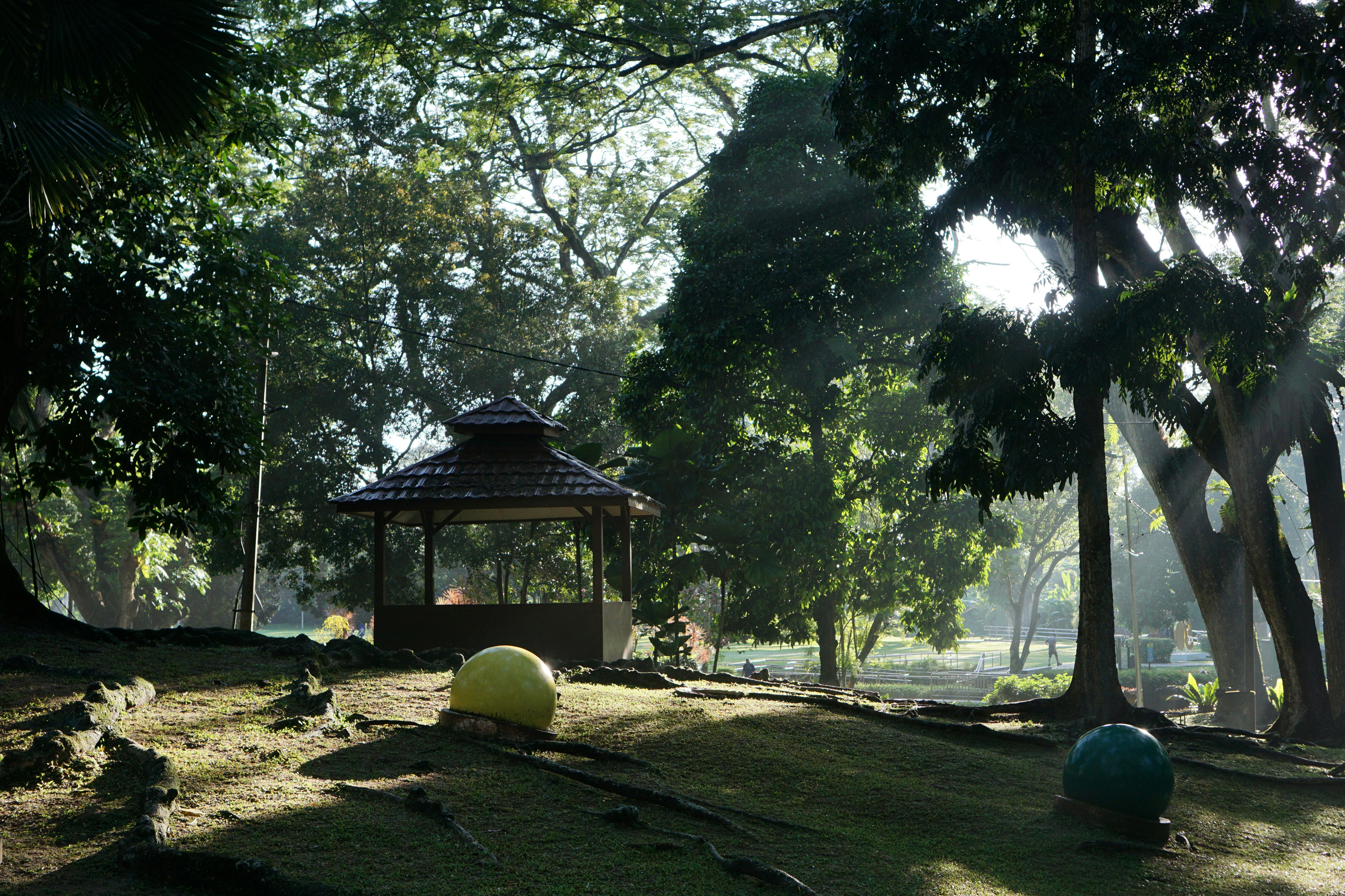 A gazebo and balls sit in a sunny park.