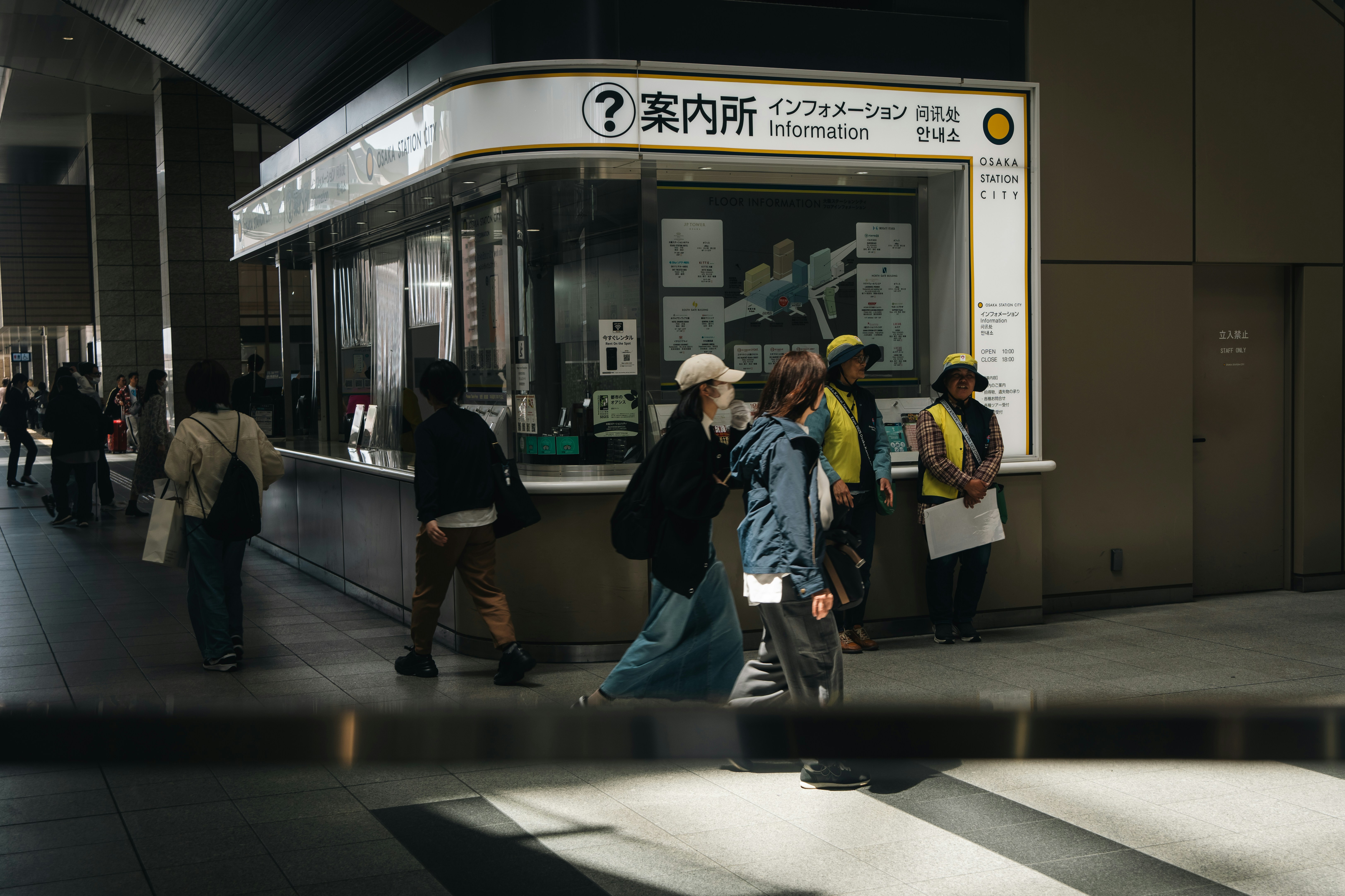 People walk past an information booth.