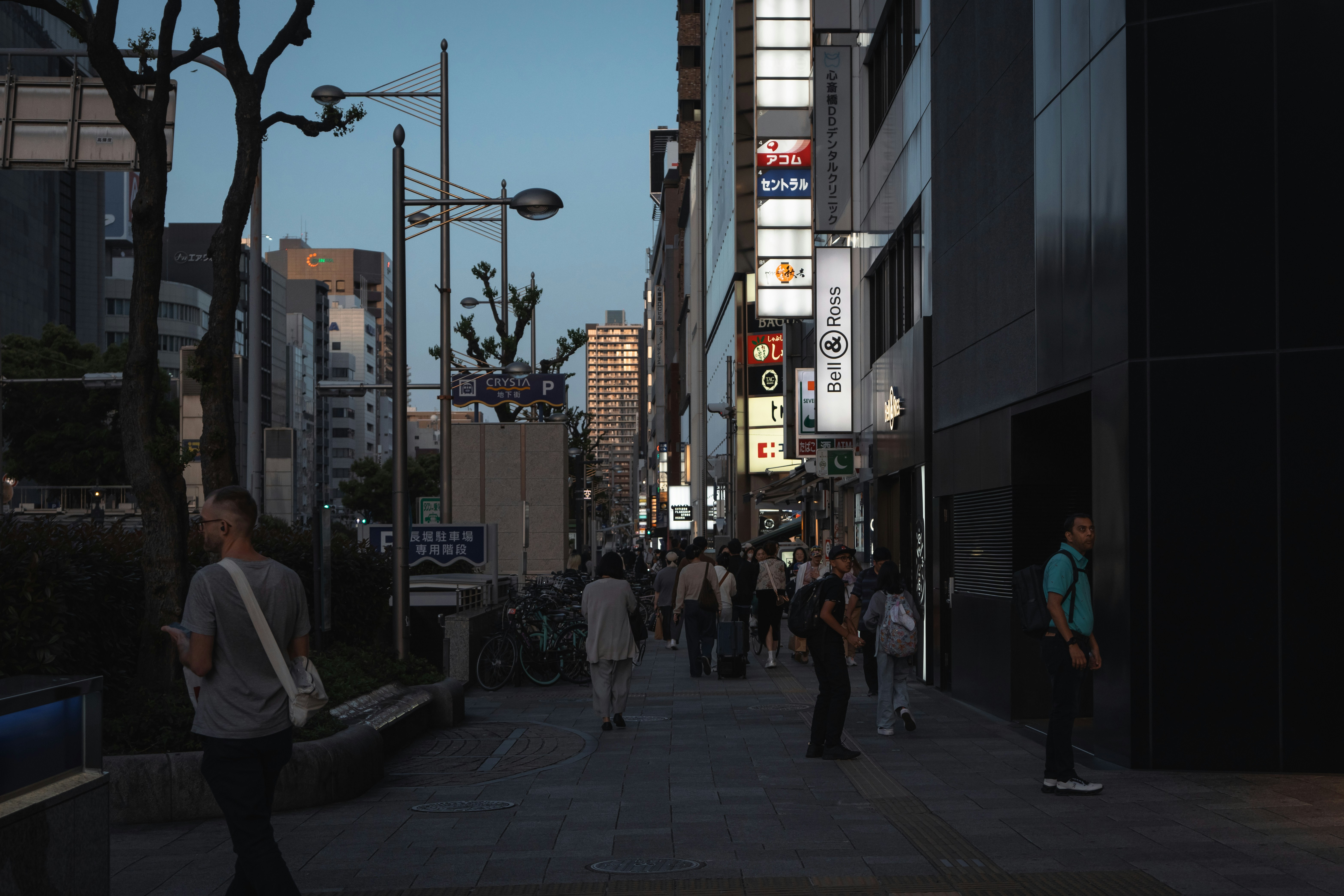 People stroll down a city street at dusk.